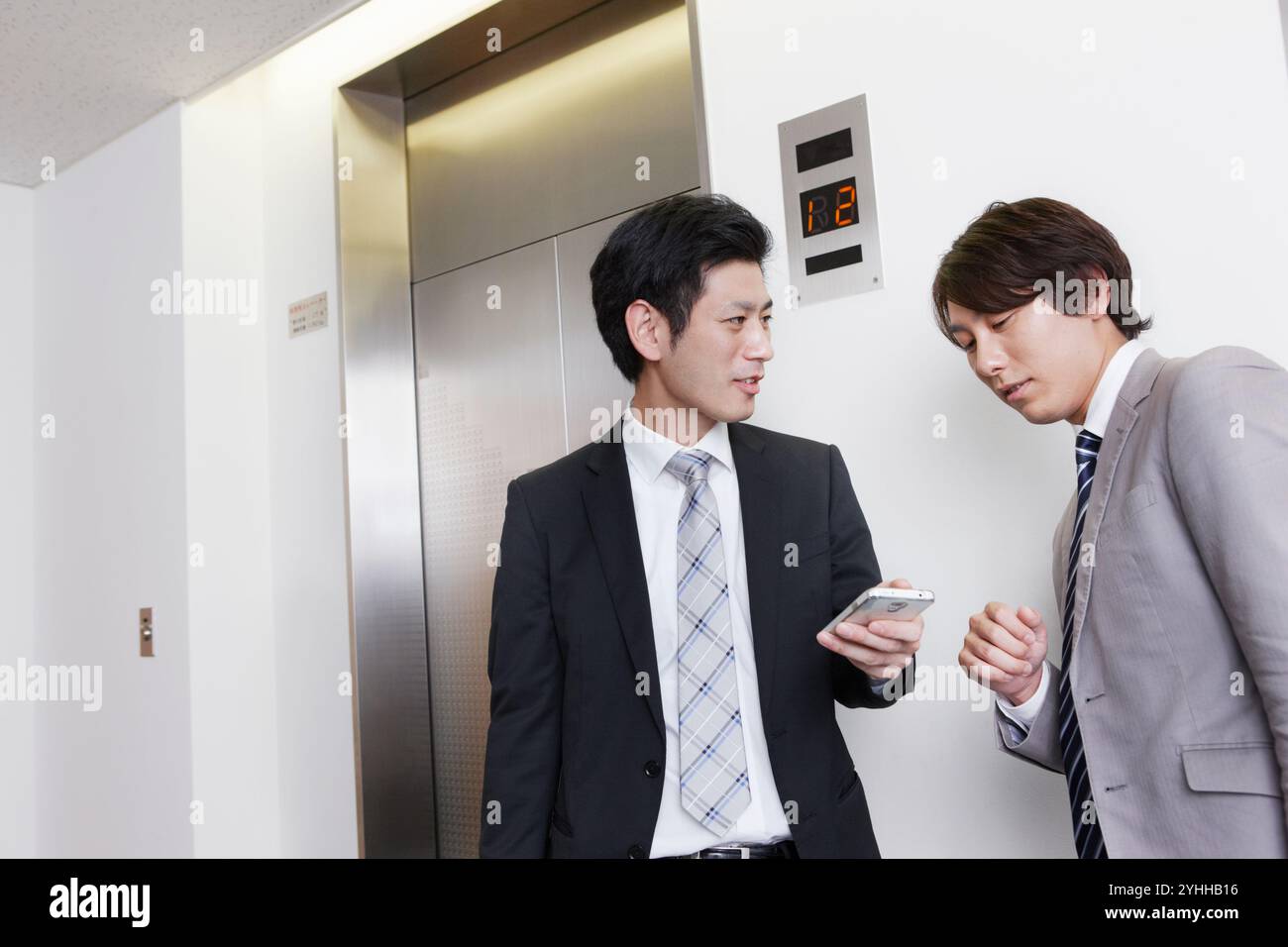 Uomo d'affari che parla davanti all'ascensore Foto Stock