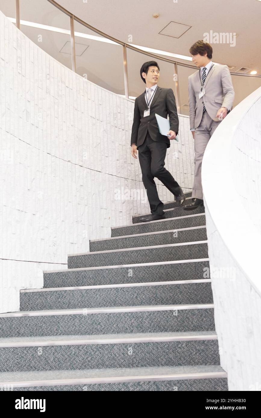 Uomo d'affari e collega che scendono le scale Foto Stock