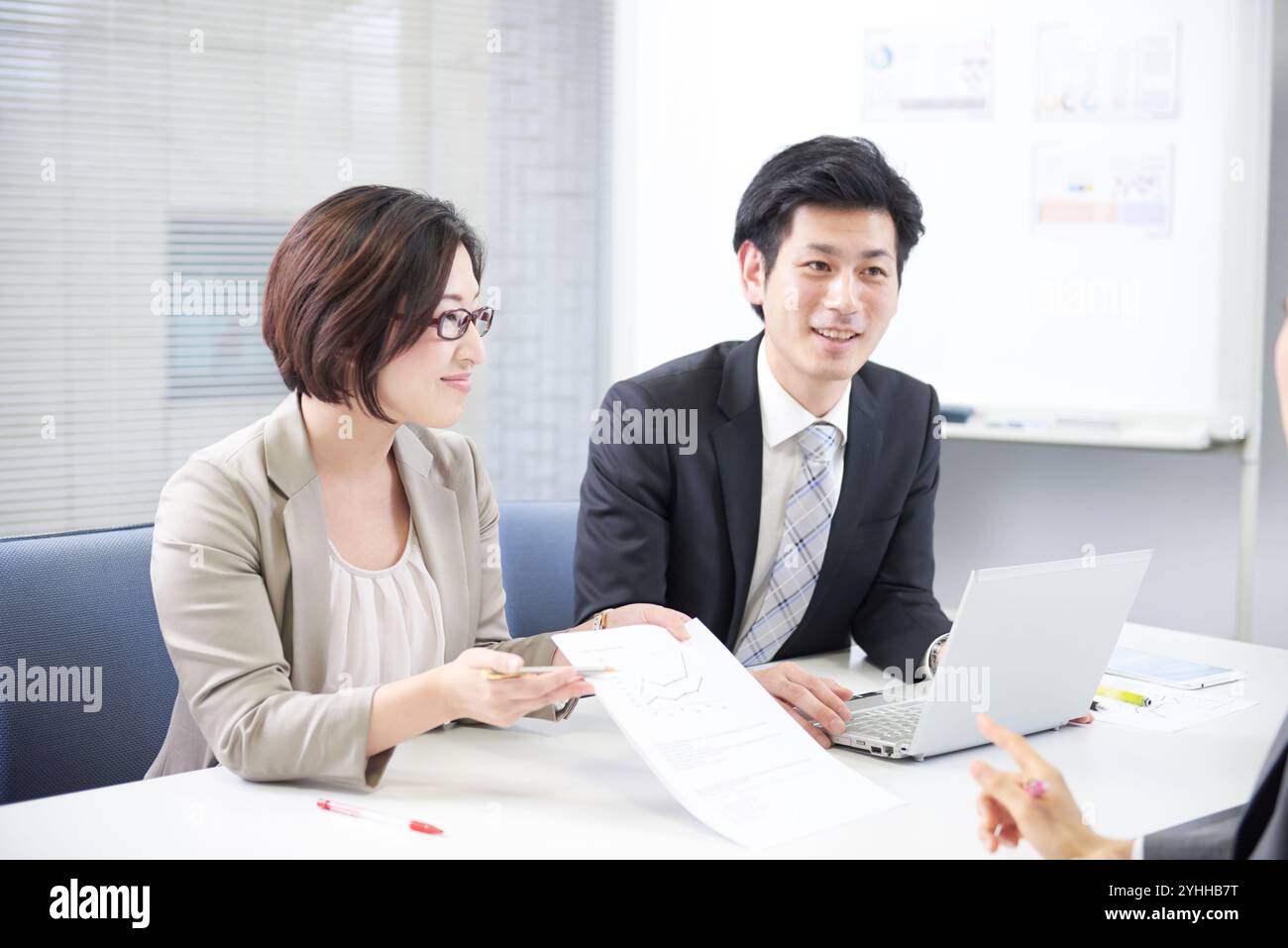 Donna in tuta e subordinata che fa un suggerimento ad una riunione Foto Stock