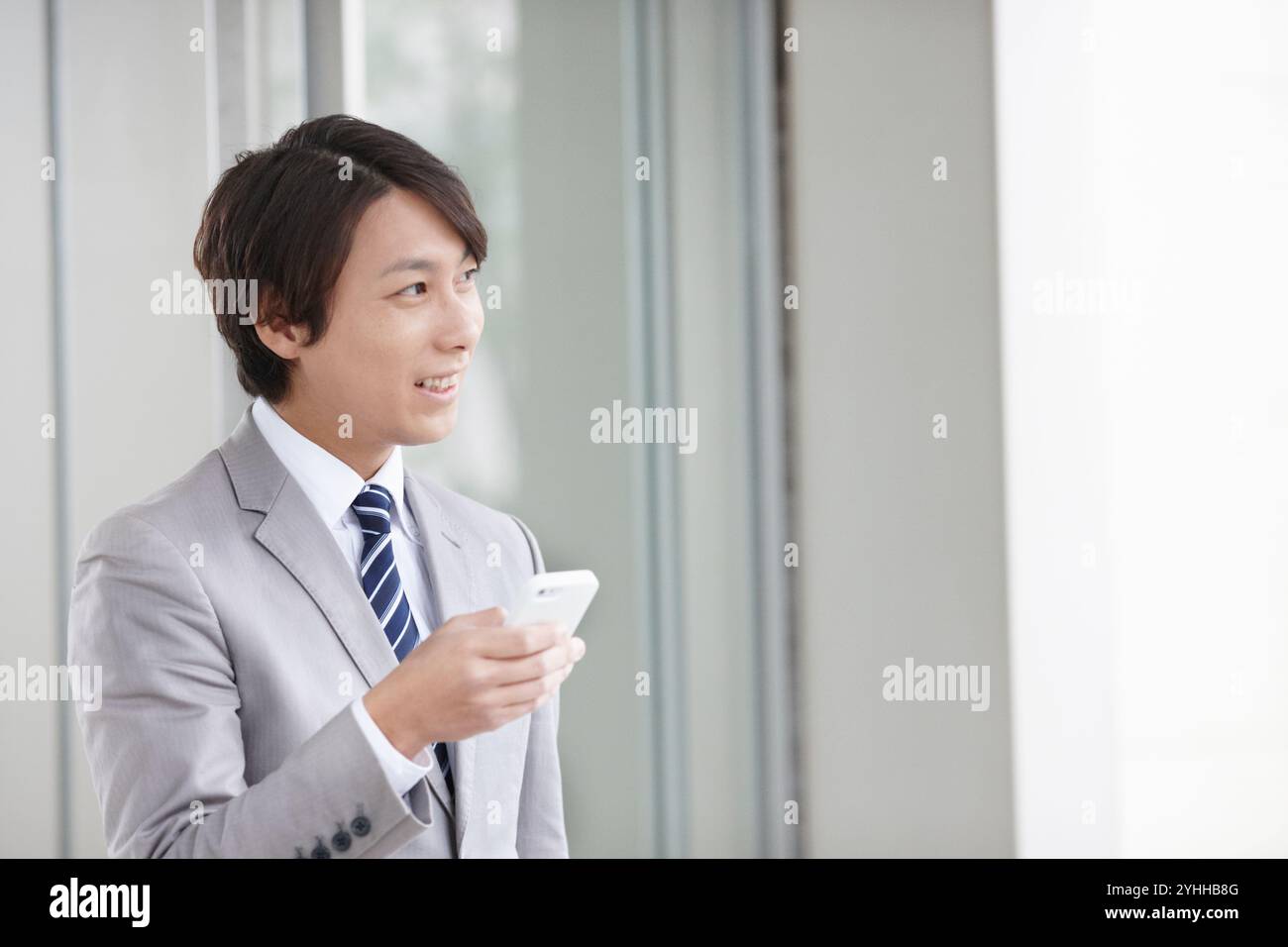 Uomo d'affari che guarda il cellulare mentre va al lavoro Foto Stock