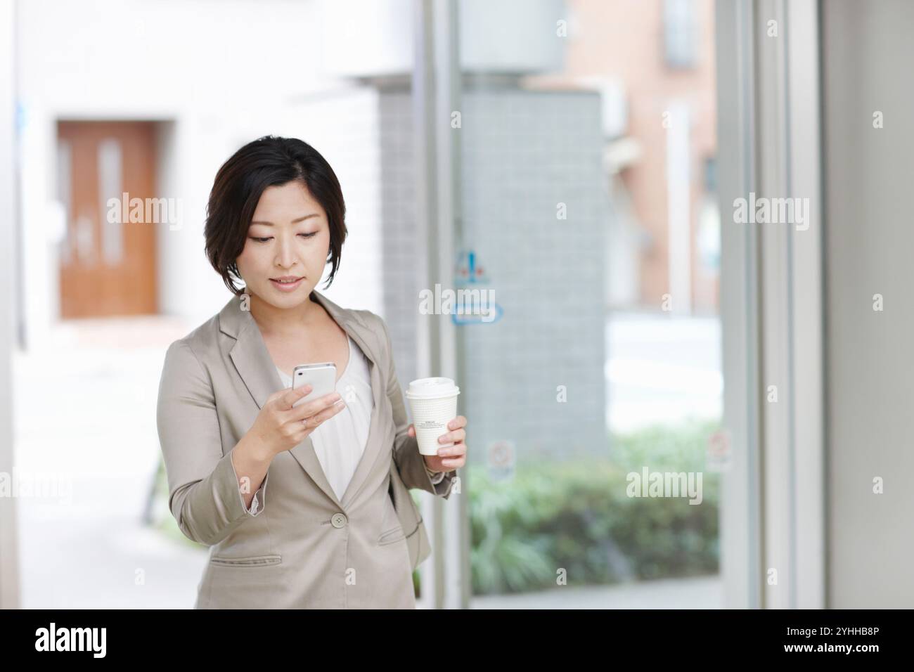 Donna d'affari che guarda il cellulare mentre va al lavoro Foto Stock