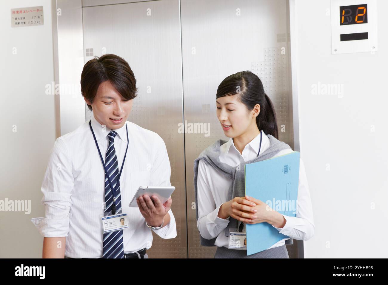 Donna e uomo d'affari che parlano davanti all'ascensore Foto Stock