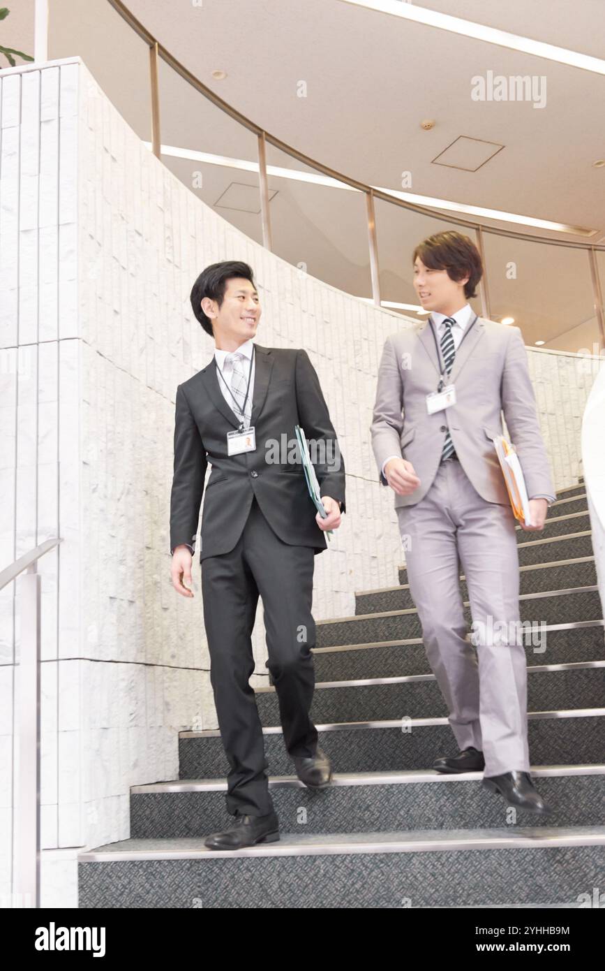 Uomo d'affari e collega che scendono le scale Foto Stock