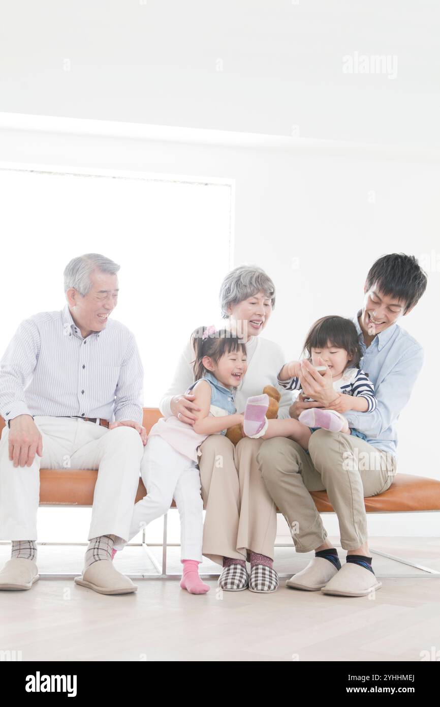 Nonno, nonna, figlio e due nipoti seduti sul divano Foto Stock