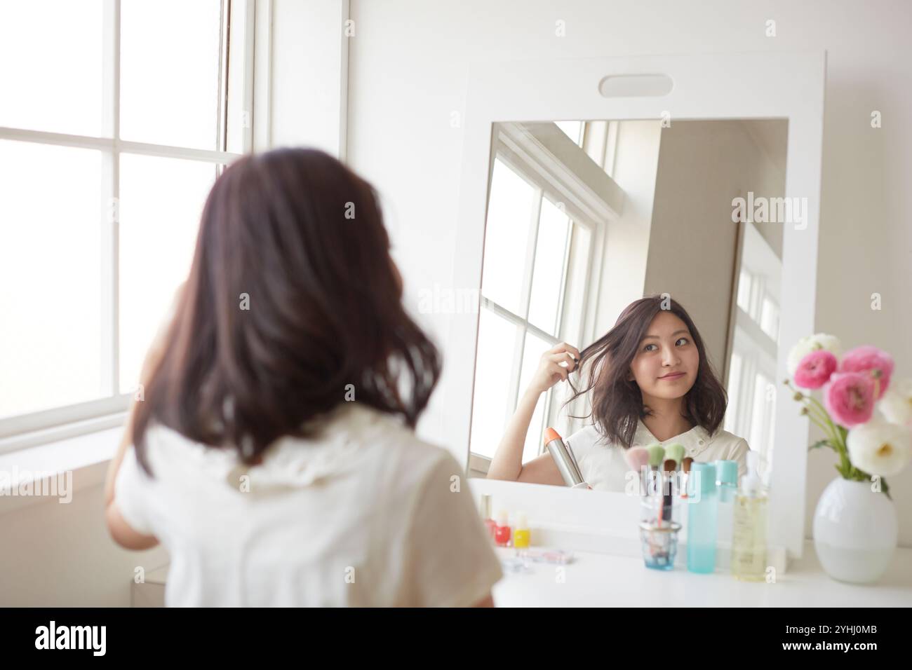 Giovane donna che si toglie i capelli allo specchio Foto Stock