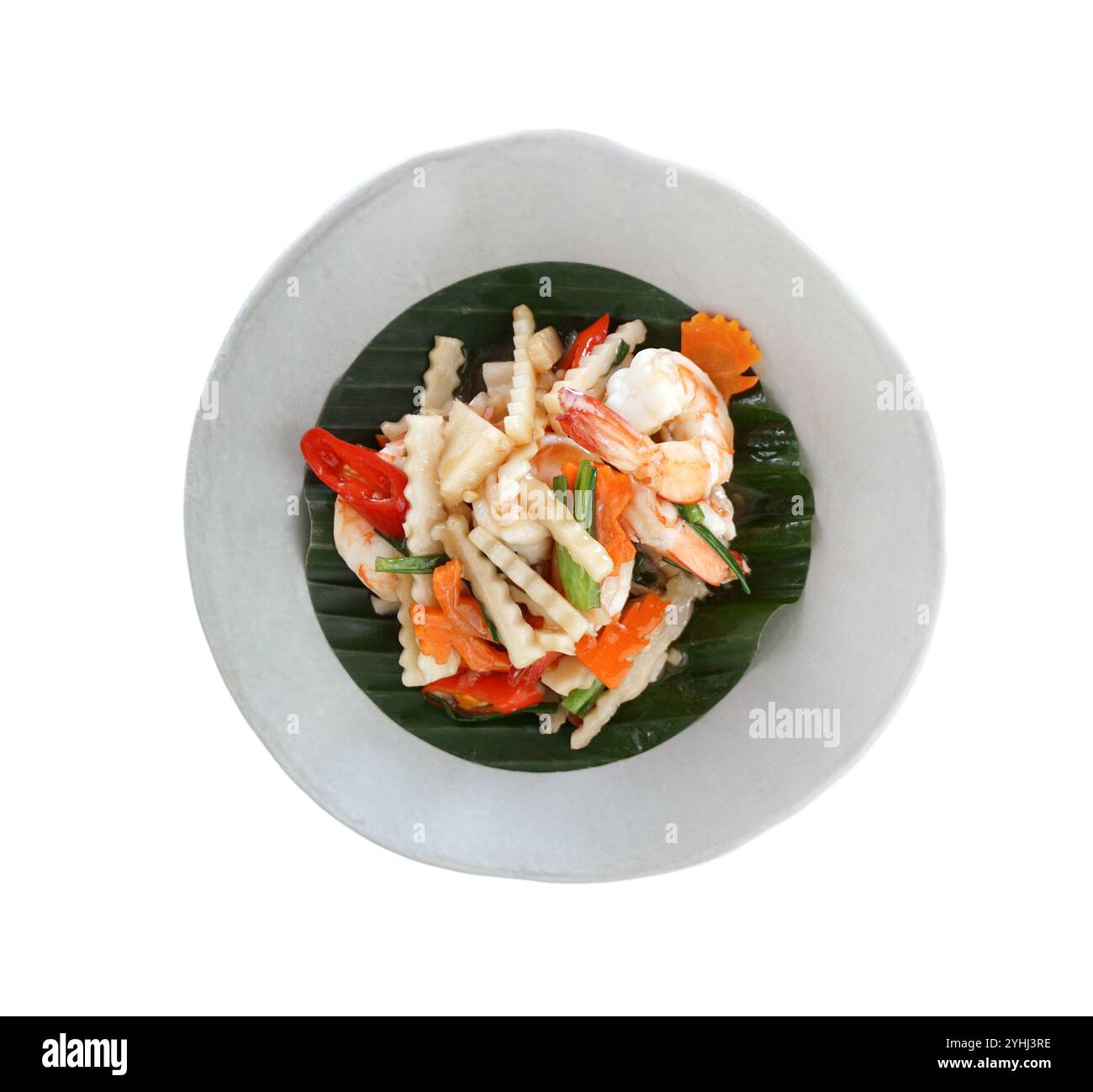 Germogli di cocco fritti in padella con gamberi in salsa di ostriche. Verdure fritte in padella in stile thailandese decorate con foglie di banana servite su un piatto bianco. Vista dall'alto Foto Stock