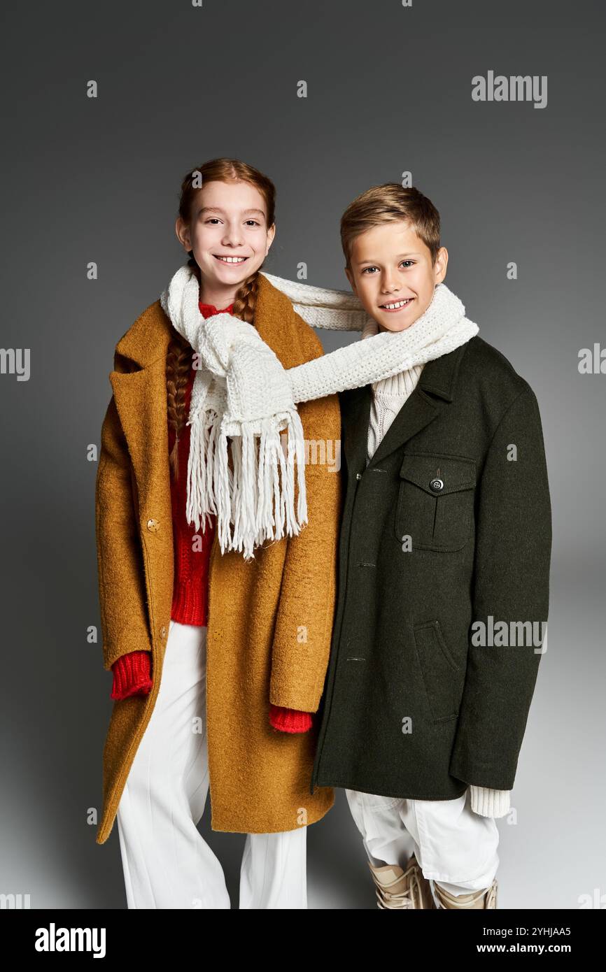 Due bambini in abiti caldi ed eleganti condividono un momento di allegria durante le festività invernali. Foto Stock