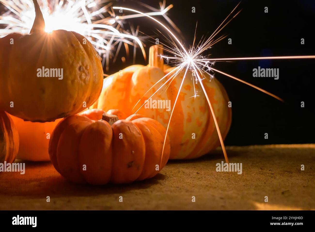 I brillanti scintillanti illuminano un gruppo di piccole zucche, creando un'atmosfera autunnale festosa e accogliente Foto Stock