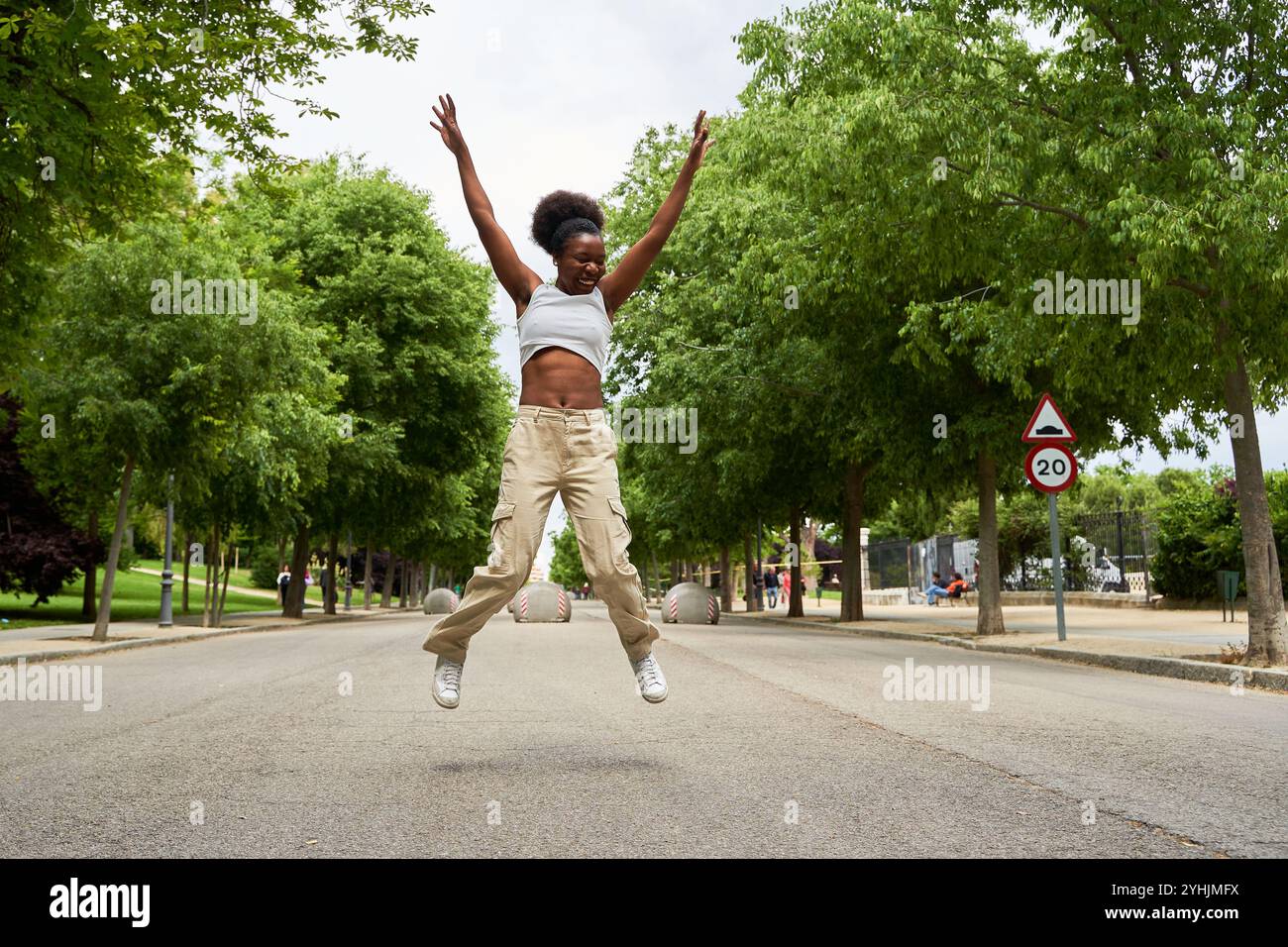 Una donna afroamericana cammina mentre ascolta la musica attraverso le sue cuffie, godendosi una fuga ritmica nella sua routine quotidiana. Foto Stock