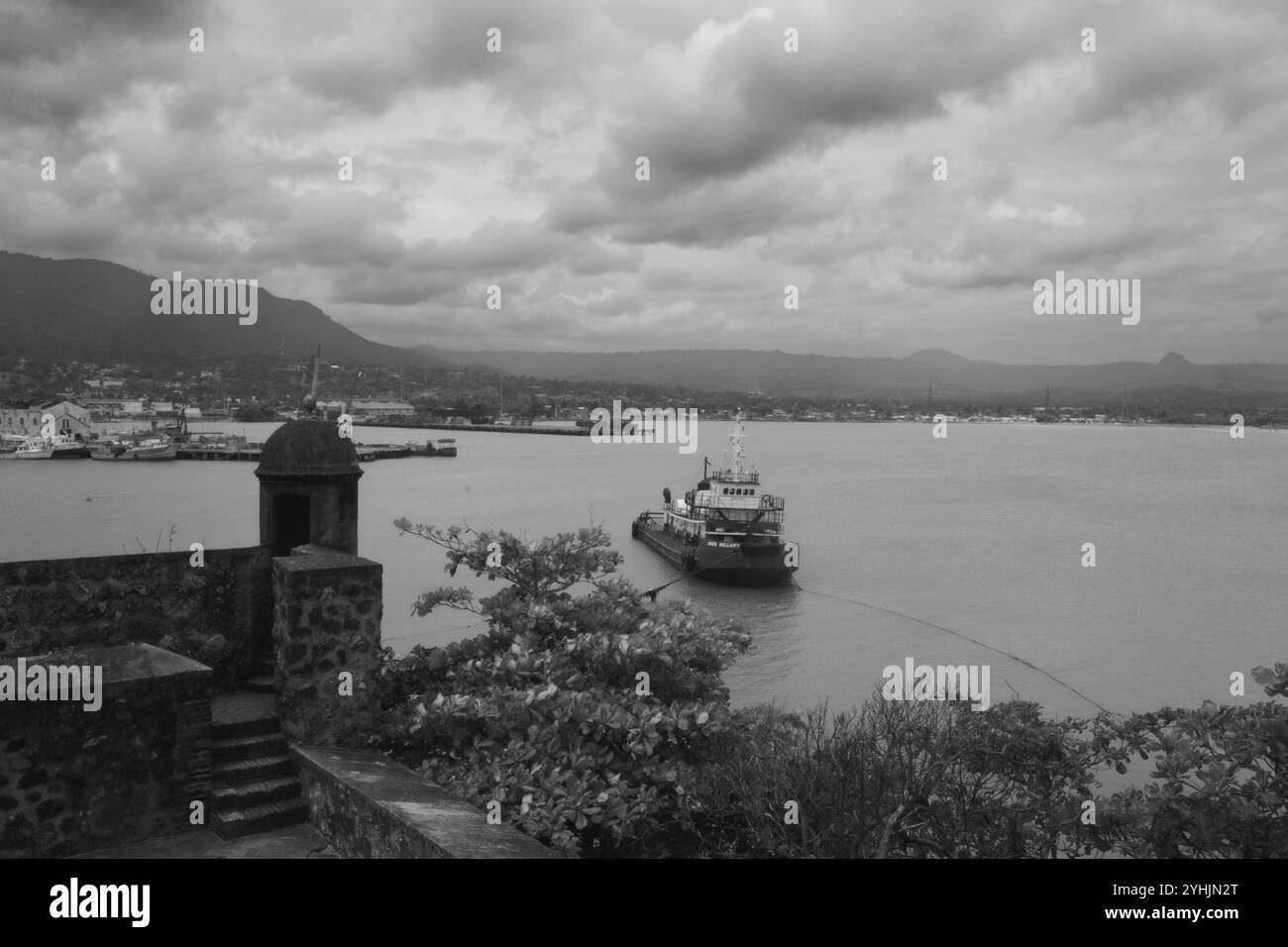 Alte palme oscillano dolcemente su una spiaggia sabbiosa, con un oceano calmo che si estende all'orizzonte sotto un cielo parzialmente nuvoloso. La scena è tranquilla. Foto Stock