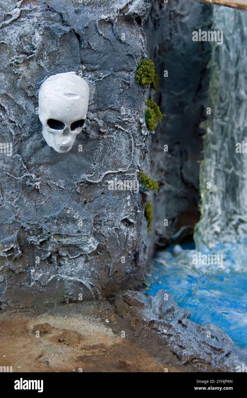 diorama modello di cranio umano sul lato della scogliera vicino a una cascata. concetto di avventura e viaggio. Foto Stock