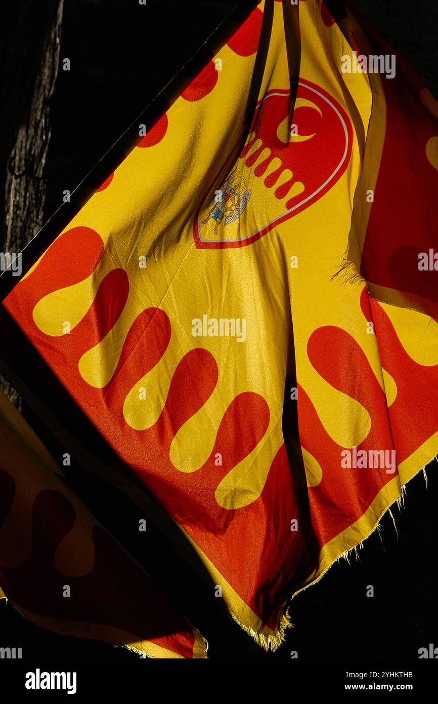 Bandiera della Contrada (quartiere storico) di Santo Agnolo a Volterra, Toscana, Italia. La bandiera originale di Santo Agnolo fu portata in battaglia nel 1236. Questa versione moderna, esposta a Volterra prima di un popolare medievale annuale, include l'emblema della luna calante della contrada e una raffigurazione di San Michele Arcangelo. Foto Stock