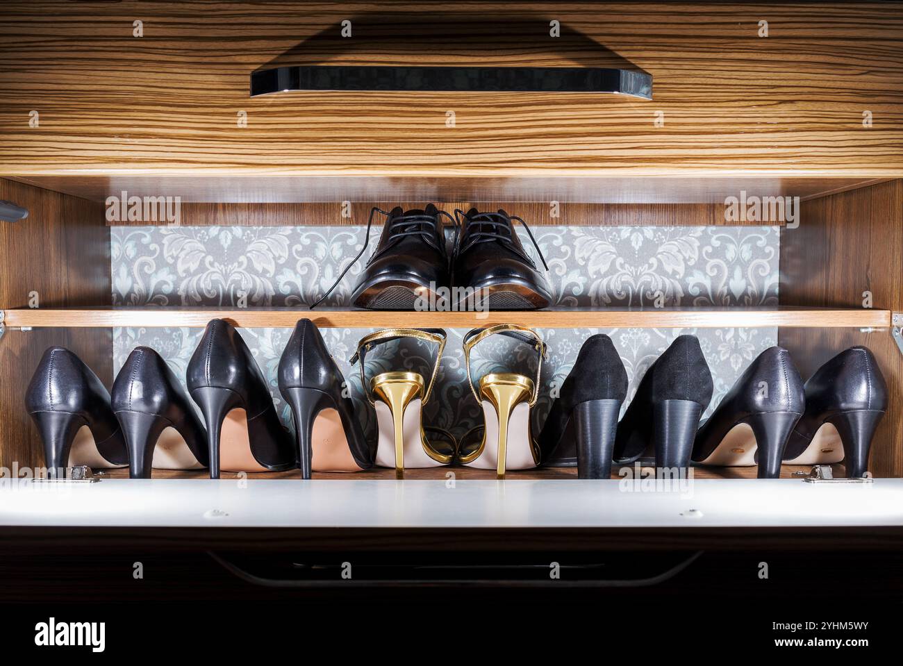 Elegante collezione di scarpe organizzata in modo ordinato in un moderno cassetto in legno Foto Stock
