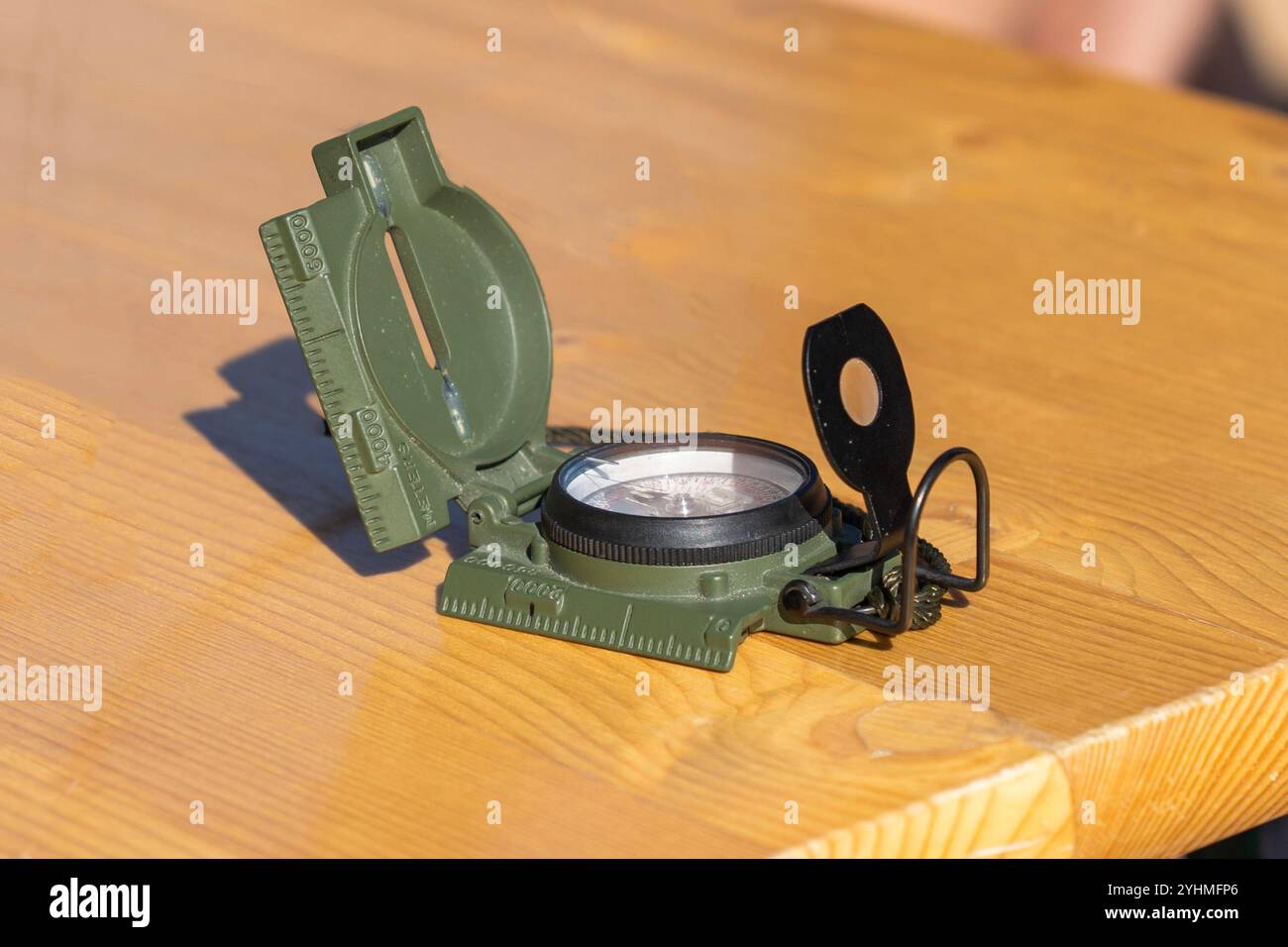 Bussola militare verde illuminata su un tavolo di legno Foto Stock