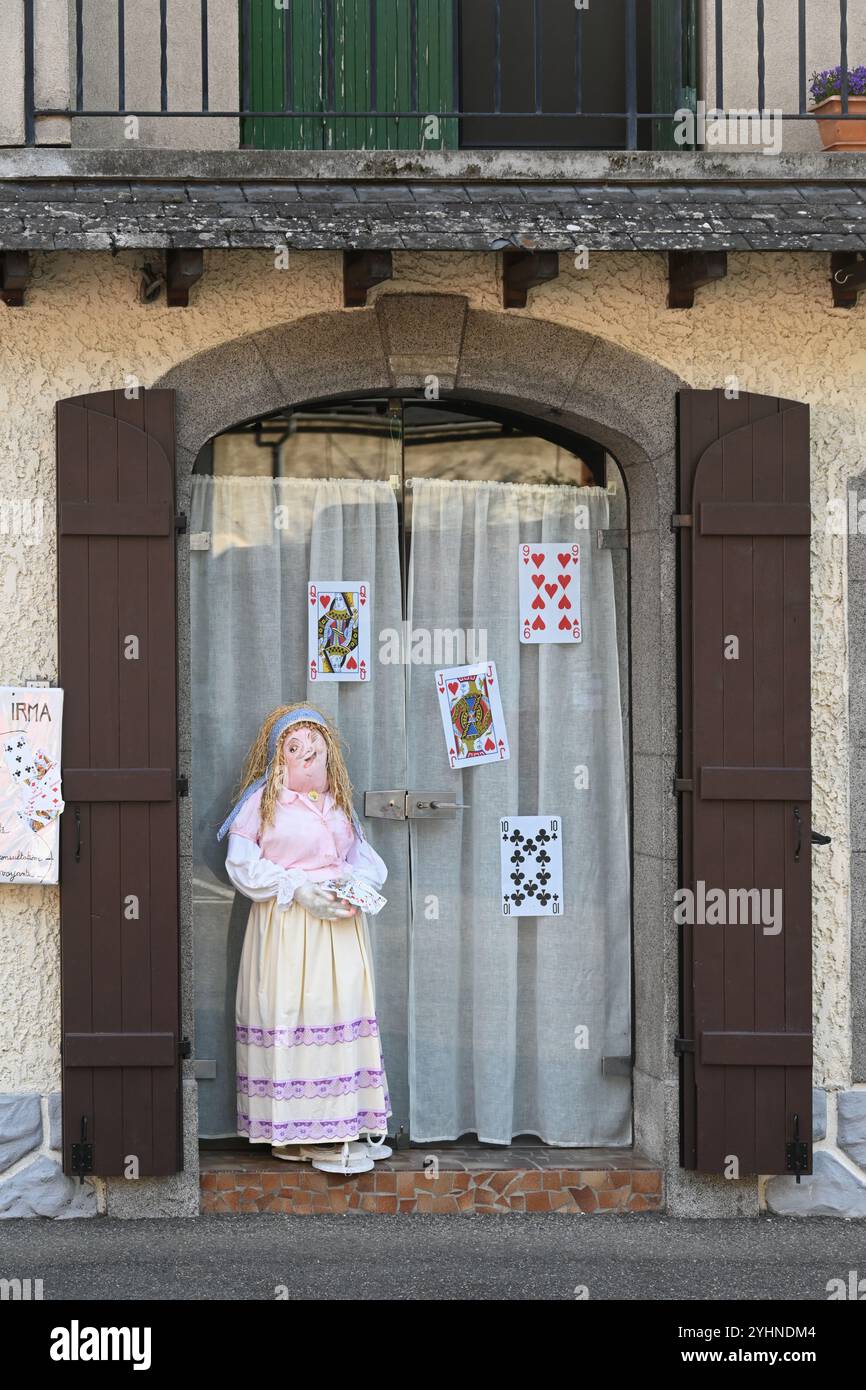 Mounaque of Campan bambola o marionetta a grandezza naturale, giocatore di carte donna al finestrino della casa del villaggio, Campan Hautes-Pyrénées Pyrenees Francia Foto Stock