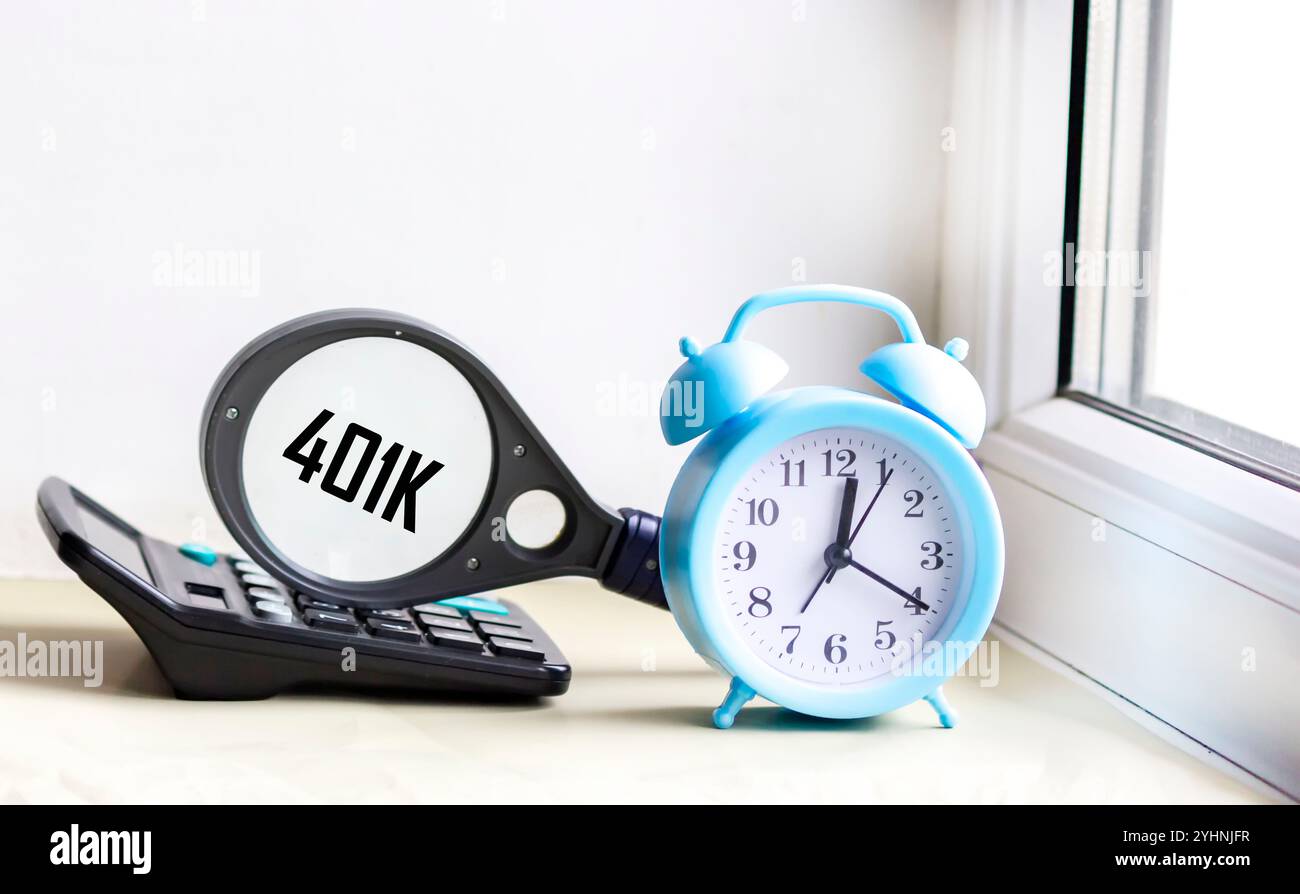La parola 401k, scritta su una lente d'ingrandimento che si trova sulla calcolatrice accanto all'orologio, è un concetto di business. Foto Stock
