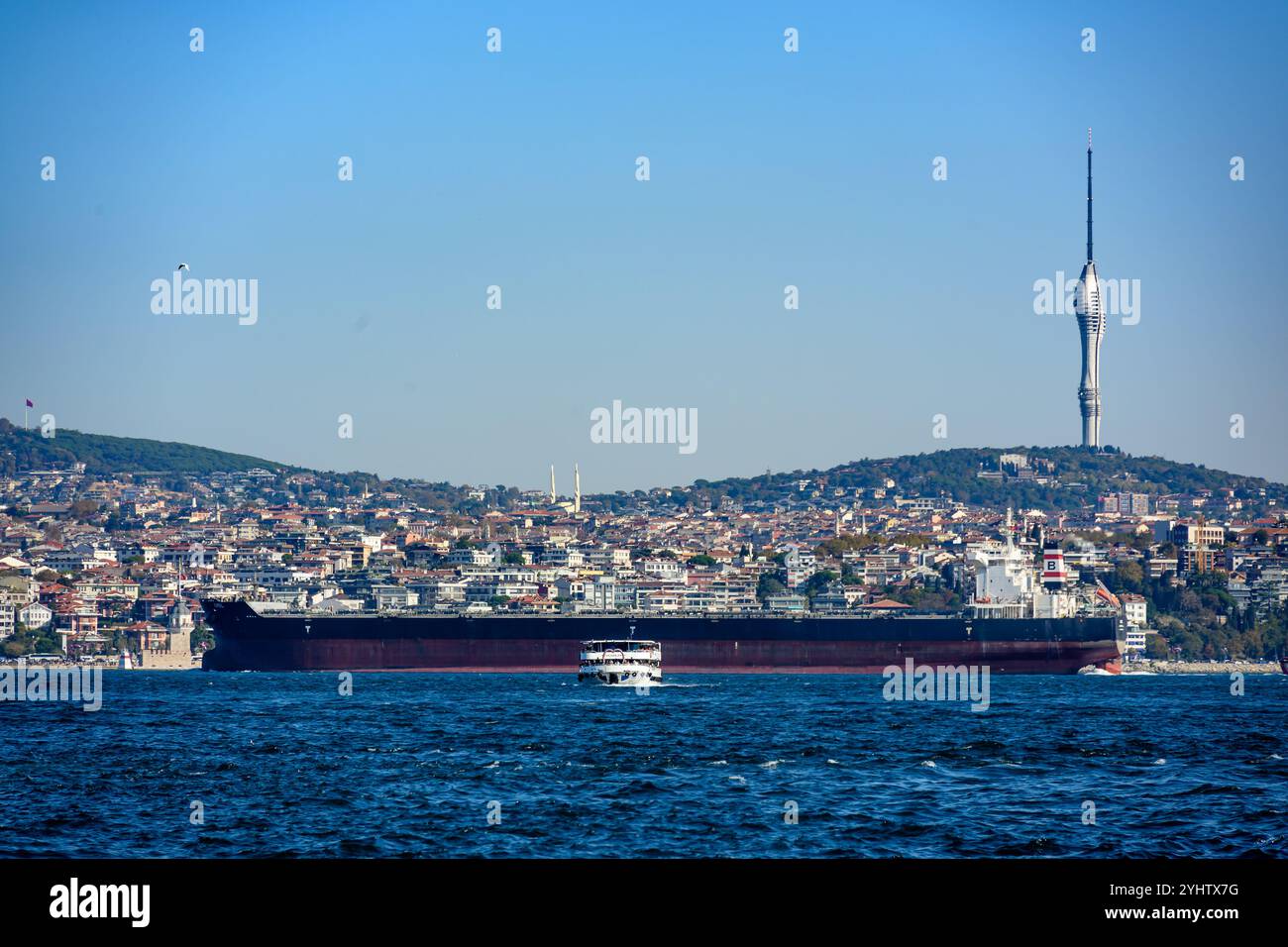 27/10/2024. Istanbul, Turchia. Una grande nave da carico che viaggia lungo il Bosphotus verso il Mar Nero per il carico di merci, con un traghetto passeggeri diretto a Eminonou, e la Torre Çamlıca sul lato asiatico di Istanbul sullo sfondo. Foto: © Simon Grosset Foto Stock