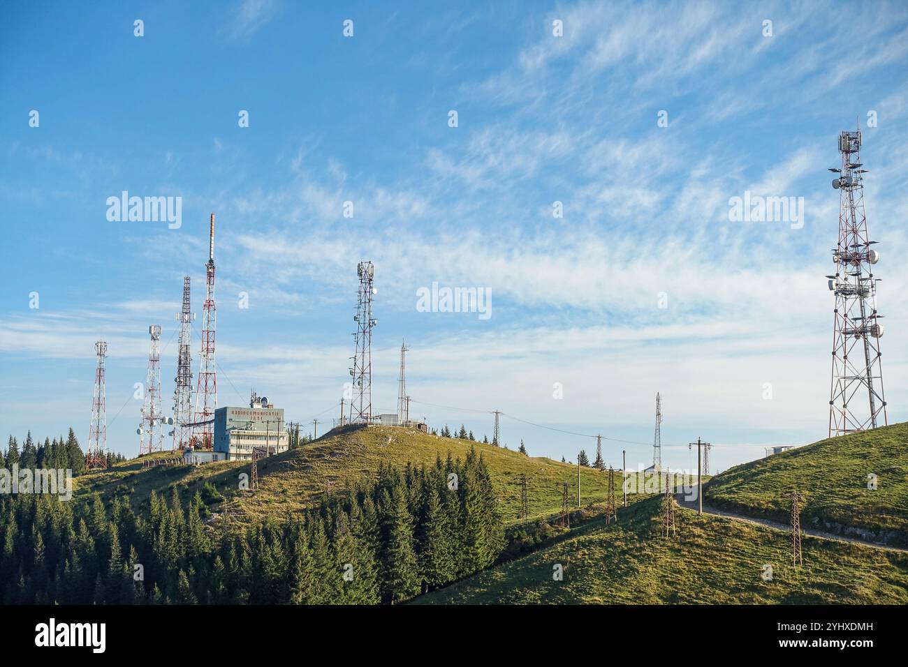 Torri di comunicazione e antenne radio su un crinale di montagna nelle montagne di Rarau in Romania sotto un cielo blu brillante con nuvole mostruose Foto Stock