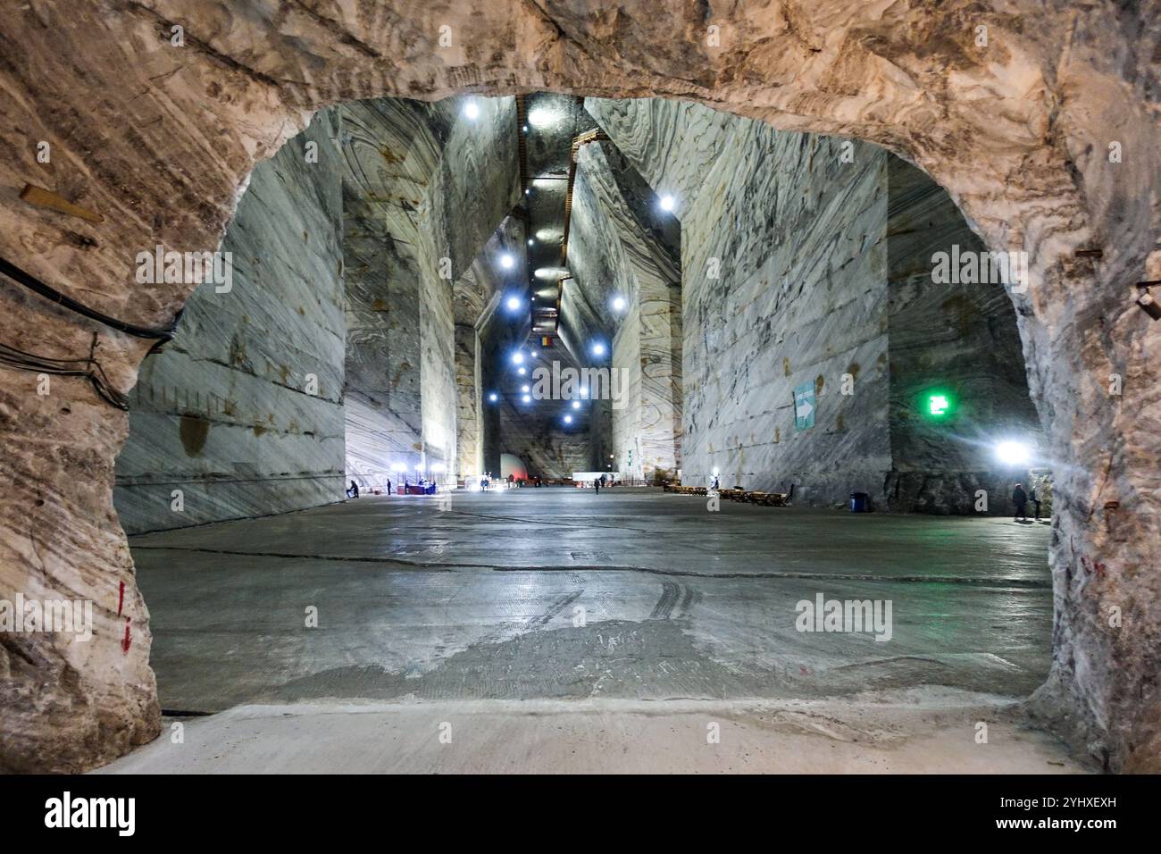 Vista interna dell'enorme camera sotterranea della miniera di sale di Slanic, Romania, con pareti illuminate, alti soffitti e un ingresso ad arco Foto Stock