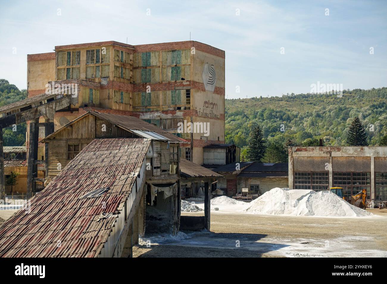 Vecchio complesso industriale abbandonato con strutture metalliche arrugginite e mucchi di minerali bianchi sopra la miniera di sale Salina Slanic, Romania Foto Stock