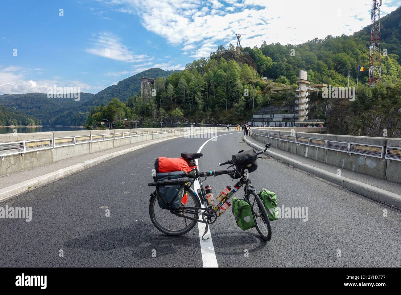 Bicicletta turistica completamente carica parcheggiata sulla diga panoramica di Vidraru, Transfăgărășan, Romania, con colline boscose Foto Stock