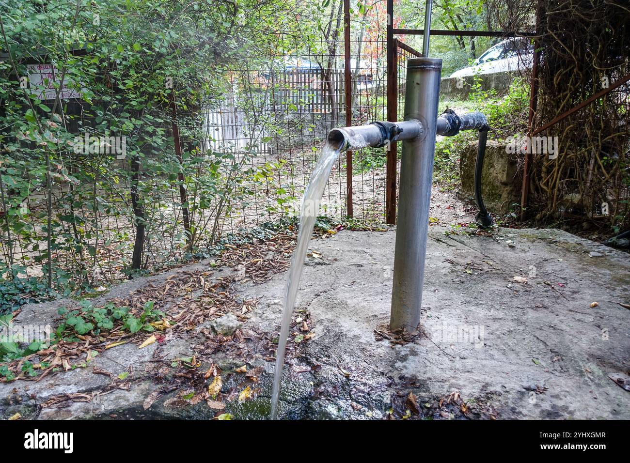 L'acqua calda fresca scorre da una fontana a tubo metallico in un ambiente rustico all'aperto, le sorgenti termali di Băile Herculane (Romania) Foto Stock