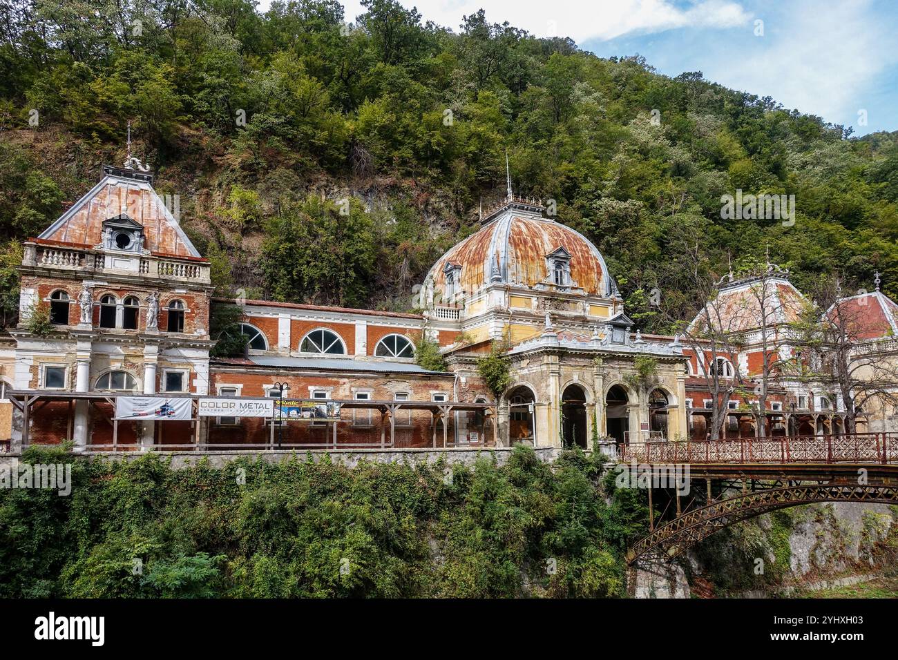 Bagni imperiali di Nettuno abbandonati a Baile Herculane, Romania, edifici storici dell'era imperiale austro-ungarica con ponte arrugginito Foto Stock