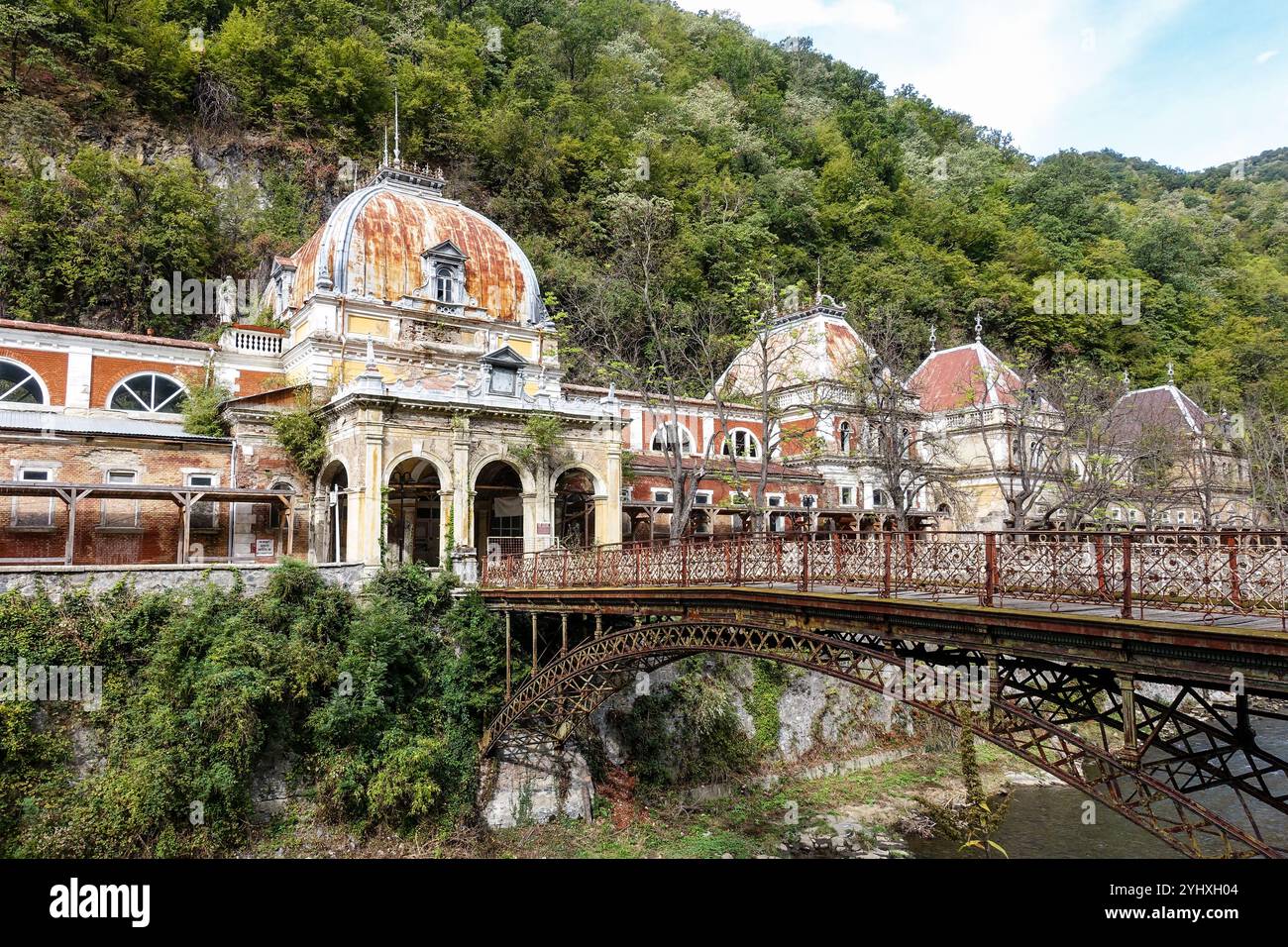 Bagni imperiali di Nettuno abbandonati a Baile Herculane, Romania, edifici storici dell'era imperiale austro-ungarica con ponte arrugginito Foto Stock