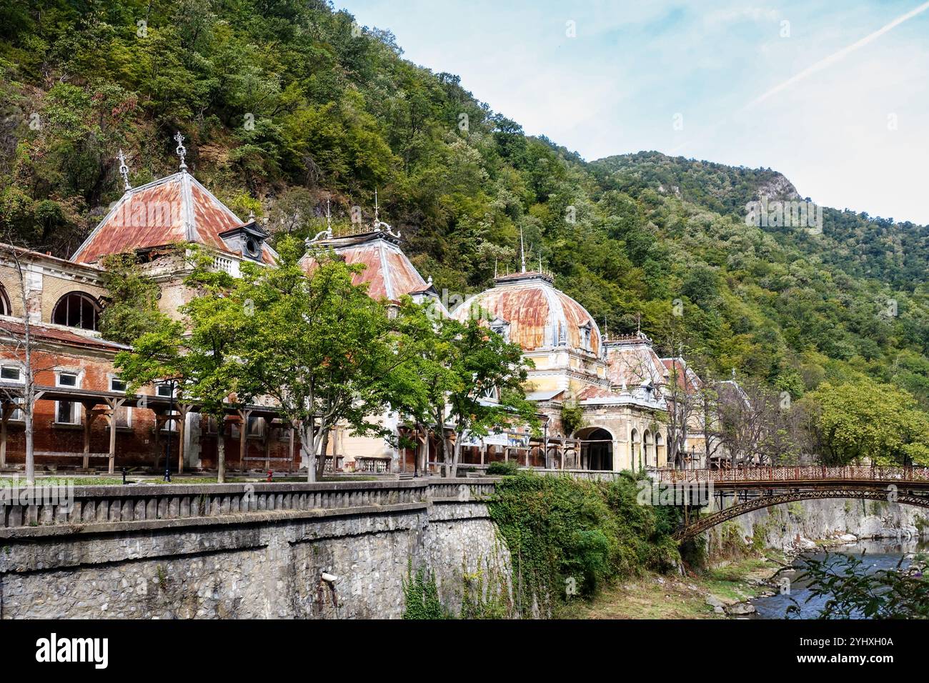 Bagni imperiali di Nettuno abbandonati a Baile Herculane, Romania, edifici storici dell'era imperiale austro-ungarica con ponte arrugginito Foto Stock