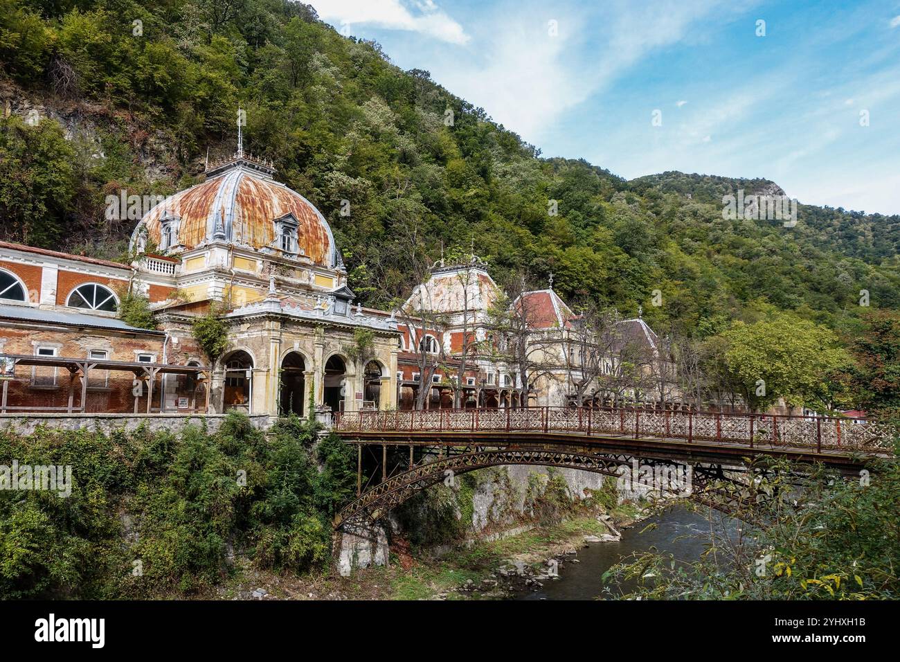 Bagni imperiali di Nettuno abbandonati a Baile Herculane, Romania, edifici storici dell'era imperiale austro-ungarica con ponte arrugginito Foto Stock