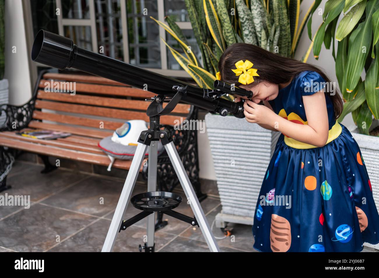 Ragazza che guarda attraverso un telescopio in un cortile Foto Stock