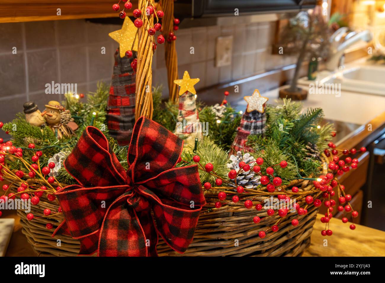 Vista ravvicinata della consistenza astratta di un cesto di vimini decorato contenente vegetazione e ornamenti natalizi, su un ripiano della cucina Foto Stock