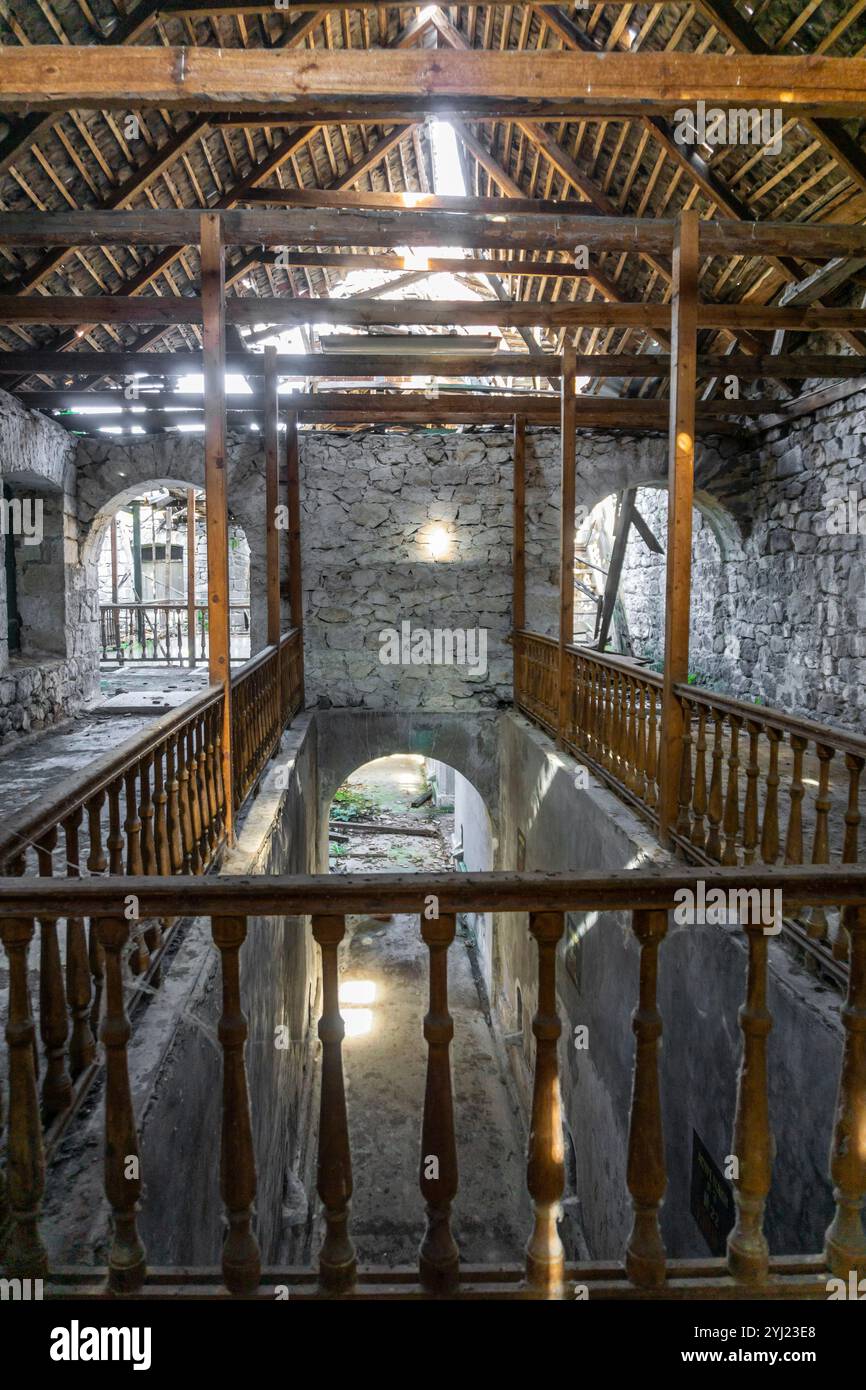 Interno di una vecchia cantina abbandonata. Pareti in pietra, ringhiere in legno, scale e finestre, tetto distrutto, lunghi corridoi, seminterrati Foto Stock