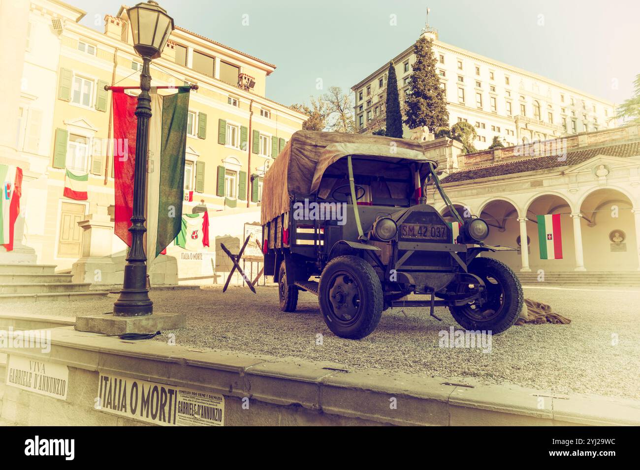 Veicoli militari della prima guerra mondiale su una splendida piazza italiana. Ricostruzione storica di una scena di guerra con furgoni militari d'epoca e cheval de frise. Foto Stock