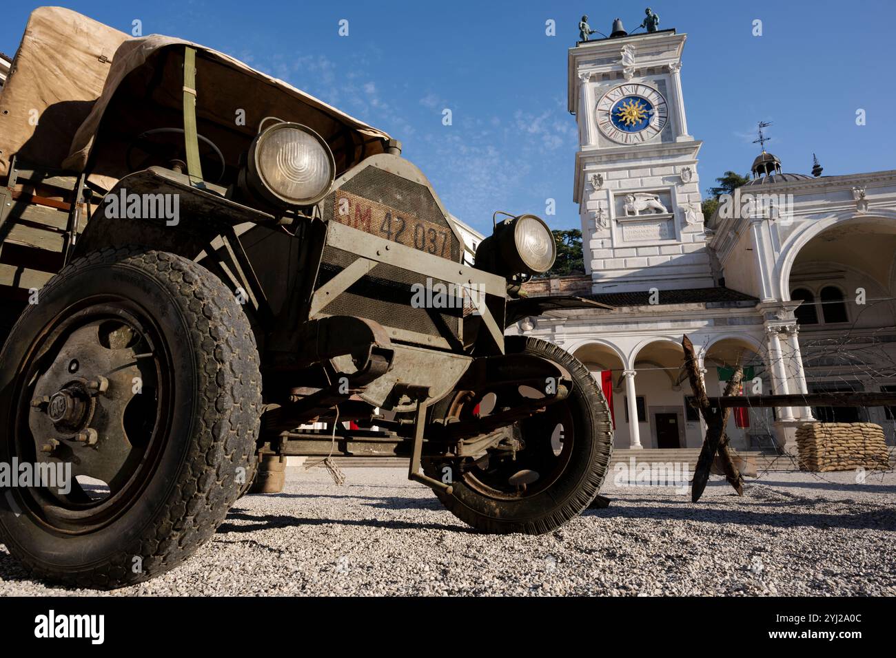 Veicoli militari della prima guerra mondiale su una splendida piazza italiana. Ricostruzione storica di una scena di guerra con furgoni militari d'epoca e cheval de frise. Foto Stock