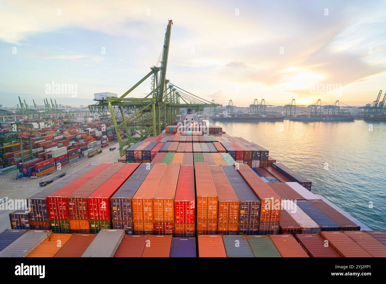 Vista aerea di una nave da carico carica di container colorati in un porto commerciale durante l'alba a Singapore Foto Stock
