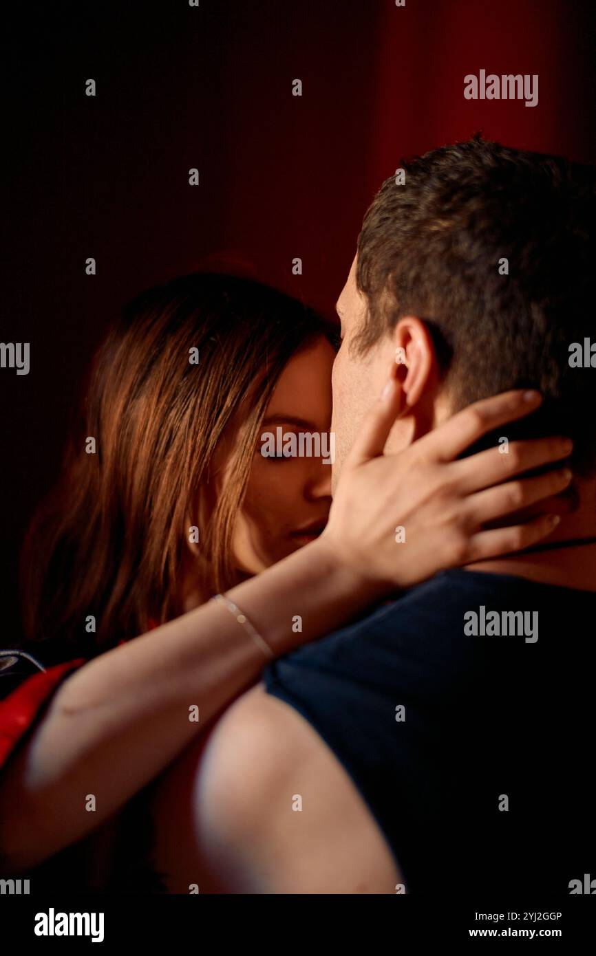 Coppia intima che abbraccia e condivide un momento romantico in una camera poco illuminata. Foto Stock