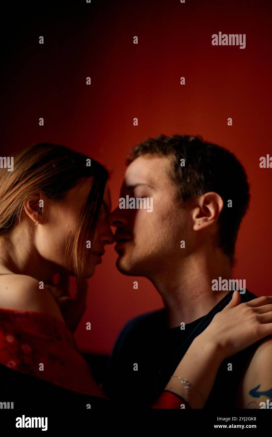 Un momento intimo tra una coppia mentre sta per baciarsi, illuminato da una calda luce ambiente. Foto Stock