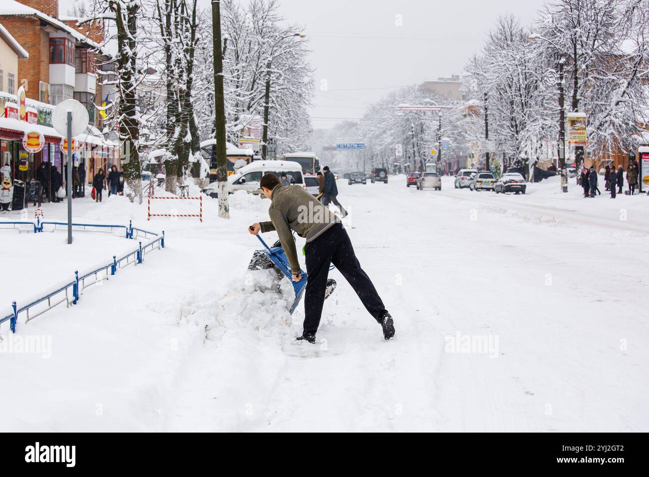 Ucraina, la città di Romny, 18 gennaio 2018: Un uomo rimuove la neve dalle strade della città durante una giornata invernale nevosa. Rimozione della neve in città e persone Foto Stock