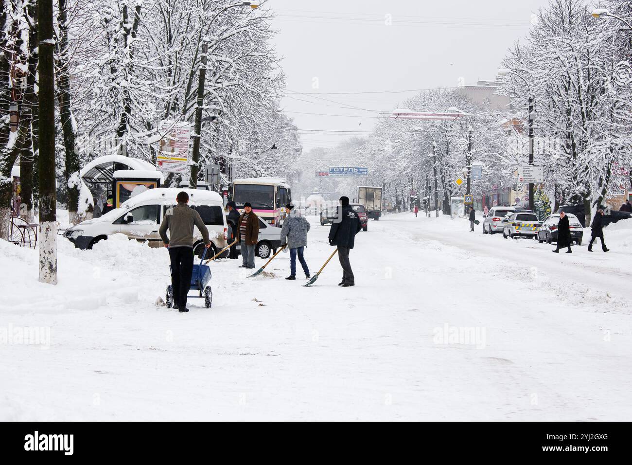 Ucraina, la città di Romny, 18 gennaio 2018: Gli uomini rimuovono la neve dalle strade della città durante una giornata invernale nevosa. Rimozione della neve urbana e delle persone Foto Stock