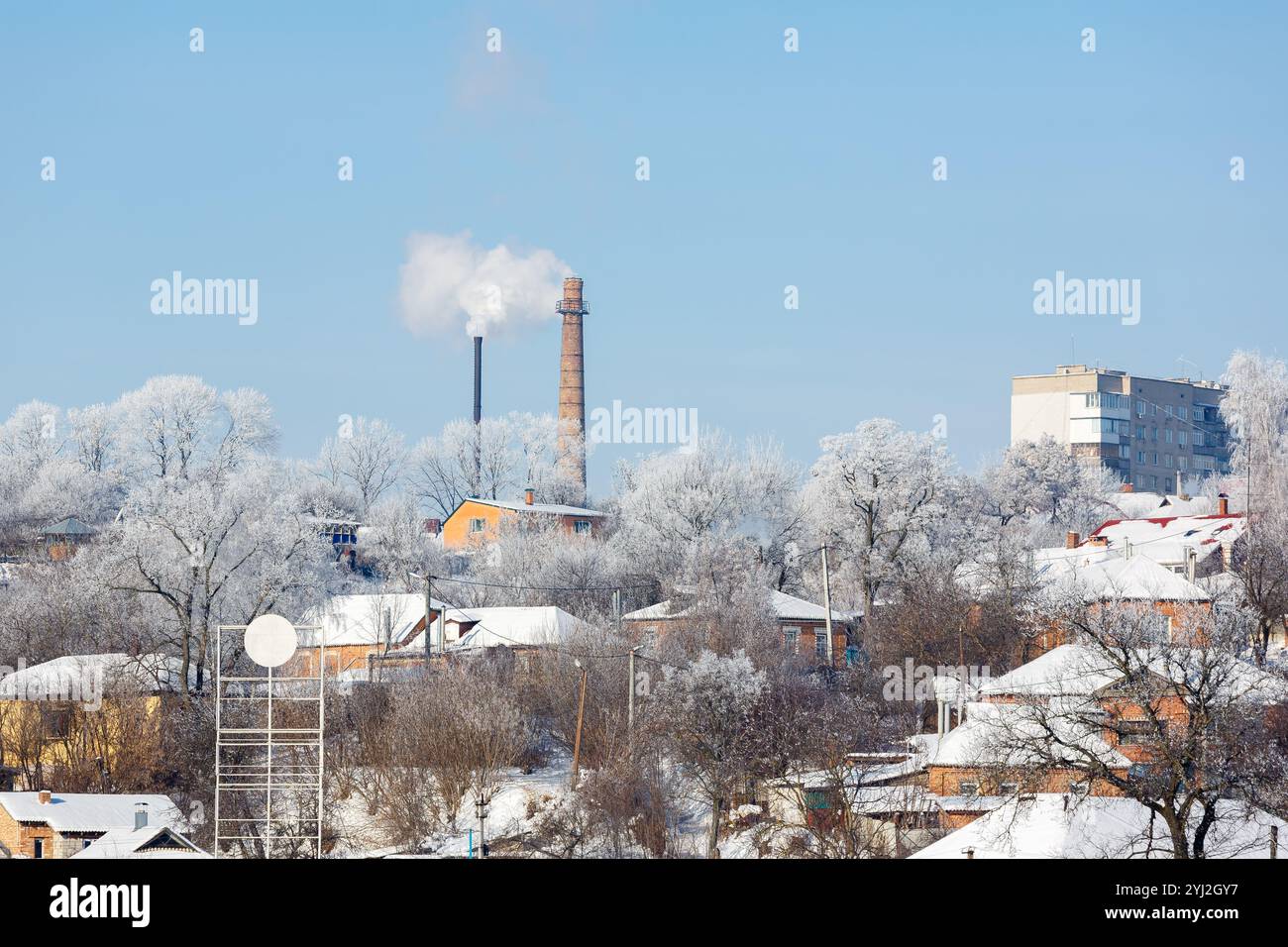 Il tubo di una caldaia a gas in città contro il cielo blu. Dal camino in mattoni fuoriesce fumo bianco. Sala caldaia in inverno. Inquinamento atmosferico. CEN Foto Stock