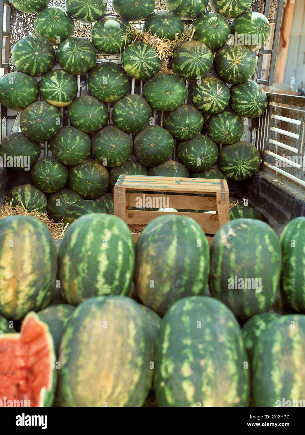 Angurie impilate in vendita in un mercato locale all'aperto, con un pezzo a fette in primo piano, il Marocco Foto Stock