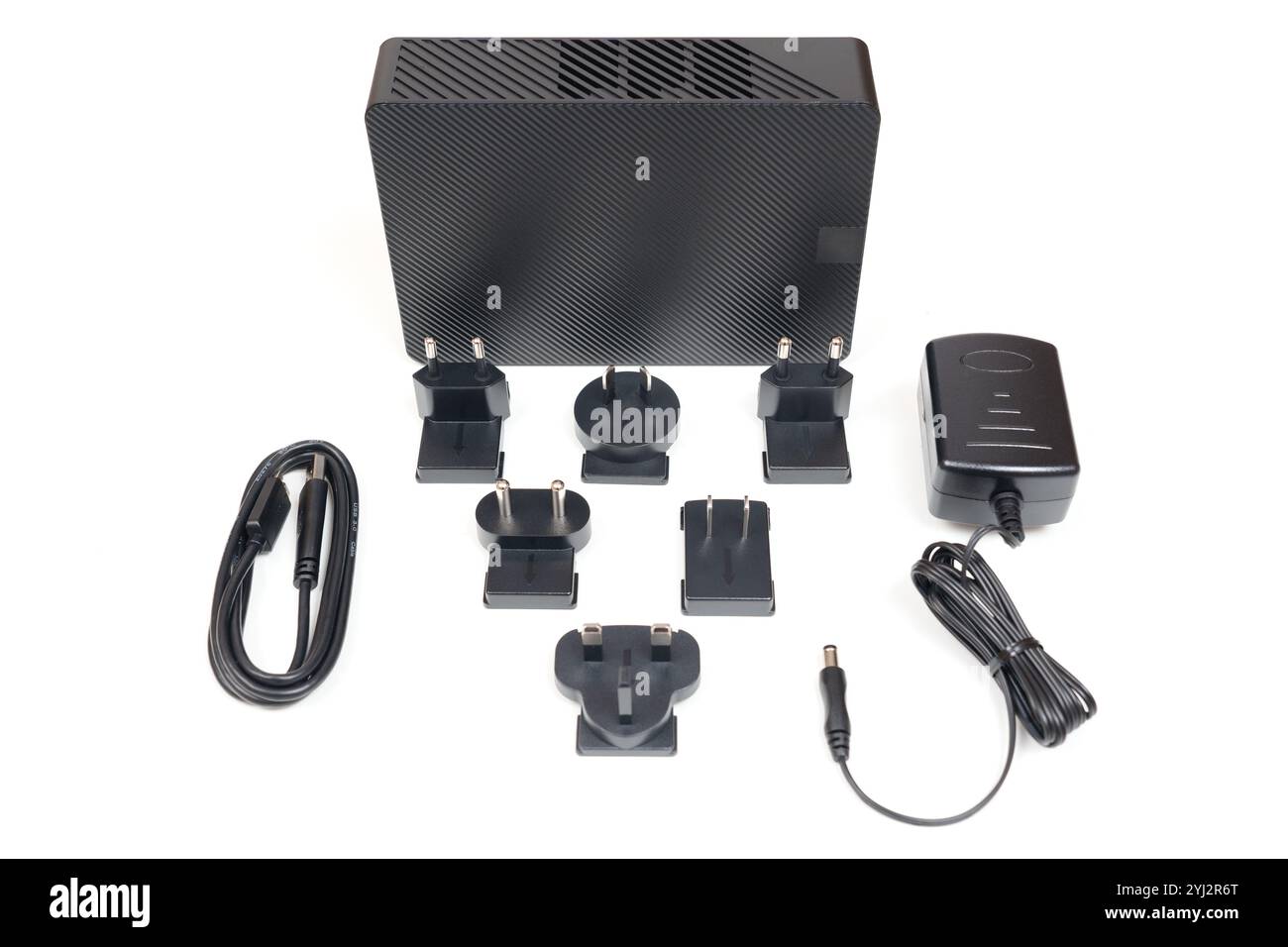 Elegante unità disco rigido nera con design in fibra di carbonio, più adattatori per spine internazionali, un alimentatore e un cavo di collegamento, il tutto sistemato in modo ordinato Foto Stock