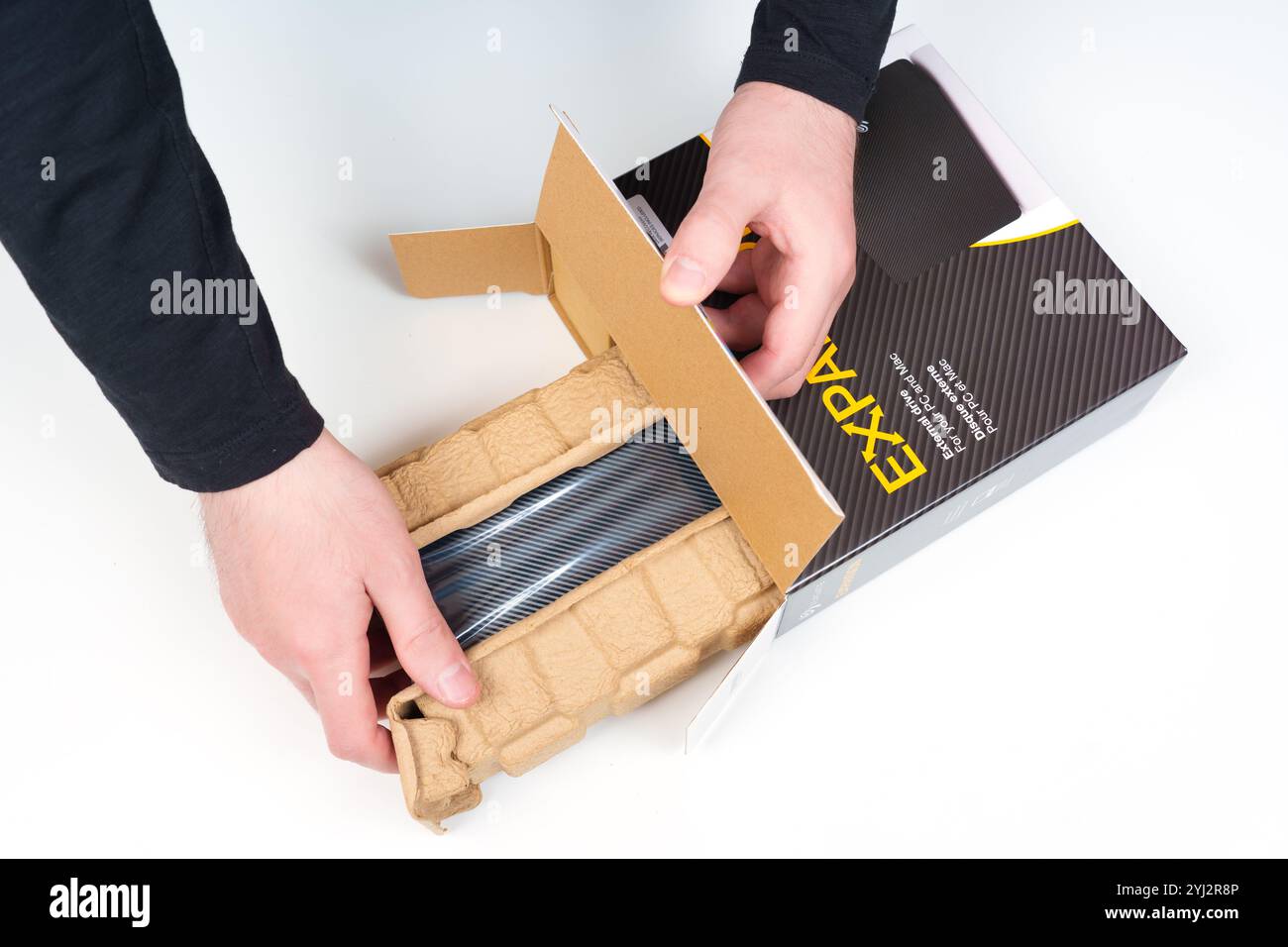 Kiev, Ucraina - 23 ottobre 2024: Mani che estraggono delicatamente il disco rigido portatile Seagate Expansion dalla confezione di cartone, evidenziando la protezione Foto Stock
