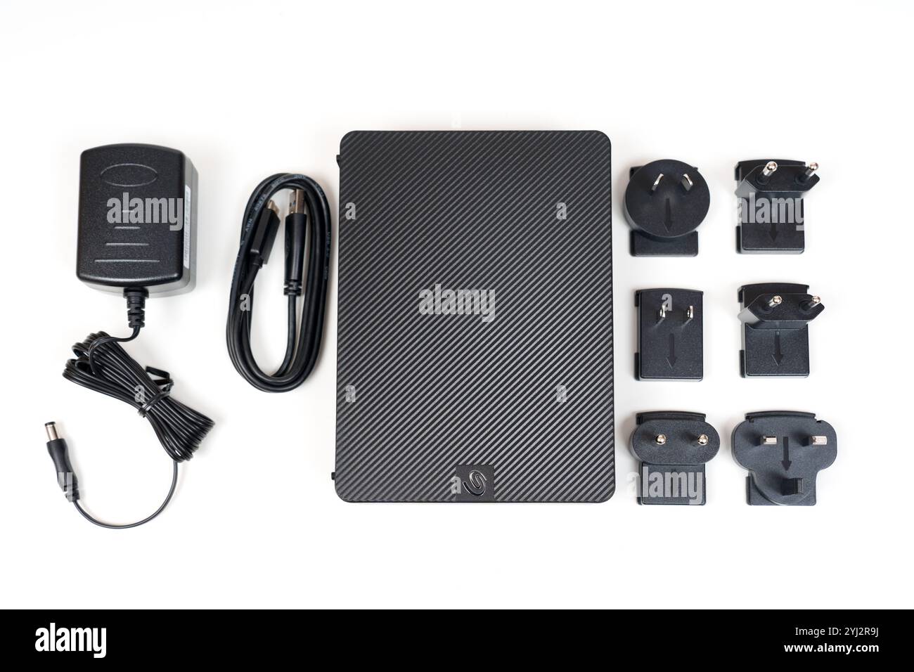 Kiev, Ucraina - 23 ottobre 2024: Disco rigido portatile Seagate Expansion accompagnato da un adattatore di alimentazione e più adattatori di spina disposti su ba bianca Foto Stock
