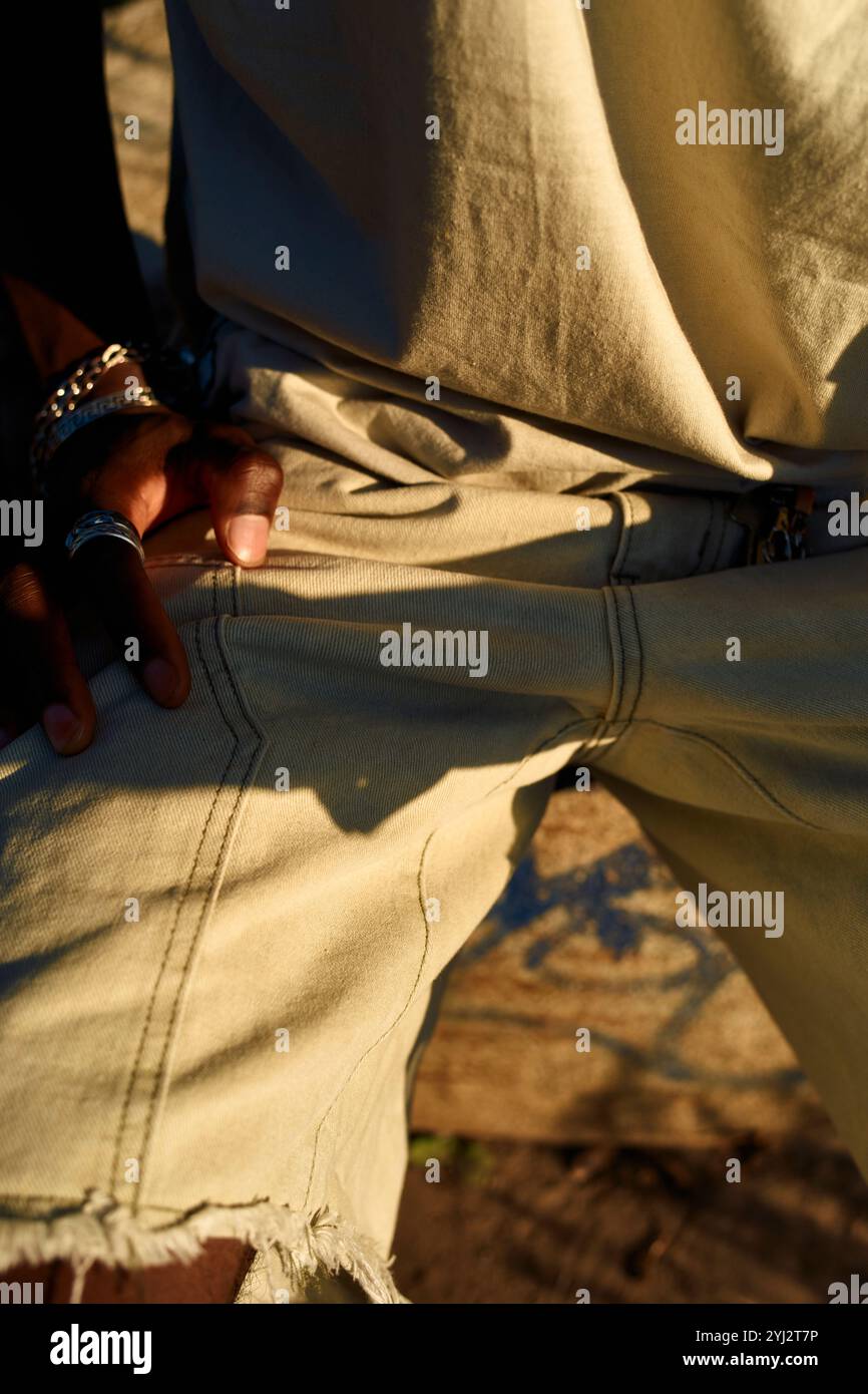 Primo piano della mano di una persona sulla tasca di jeans in jeans in jeans effetto sdrucciolevole, decorato con un anello in argento, inondato dalla calda luce del sole, Berlino, Germania Foto Stock