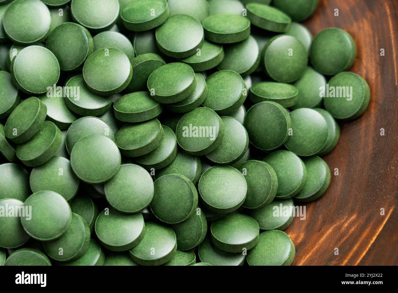 Primo piano di pillole di spirulina verdi in un recipiente di legno. Compresse nutrienti naturali con disintossicazione sana benefici da alghe dense di nutrienti Foto Stock Primo piano di pillole di spirulina verdi in un recipiente di legno. Compresse nutrienti naturali con disintossicazione sana benefici da alghe dense di nutrienti Foto Stock