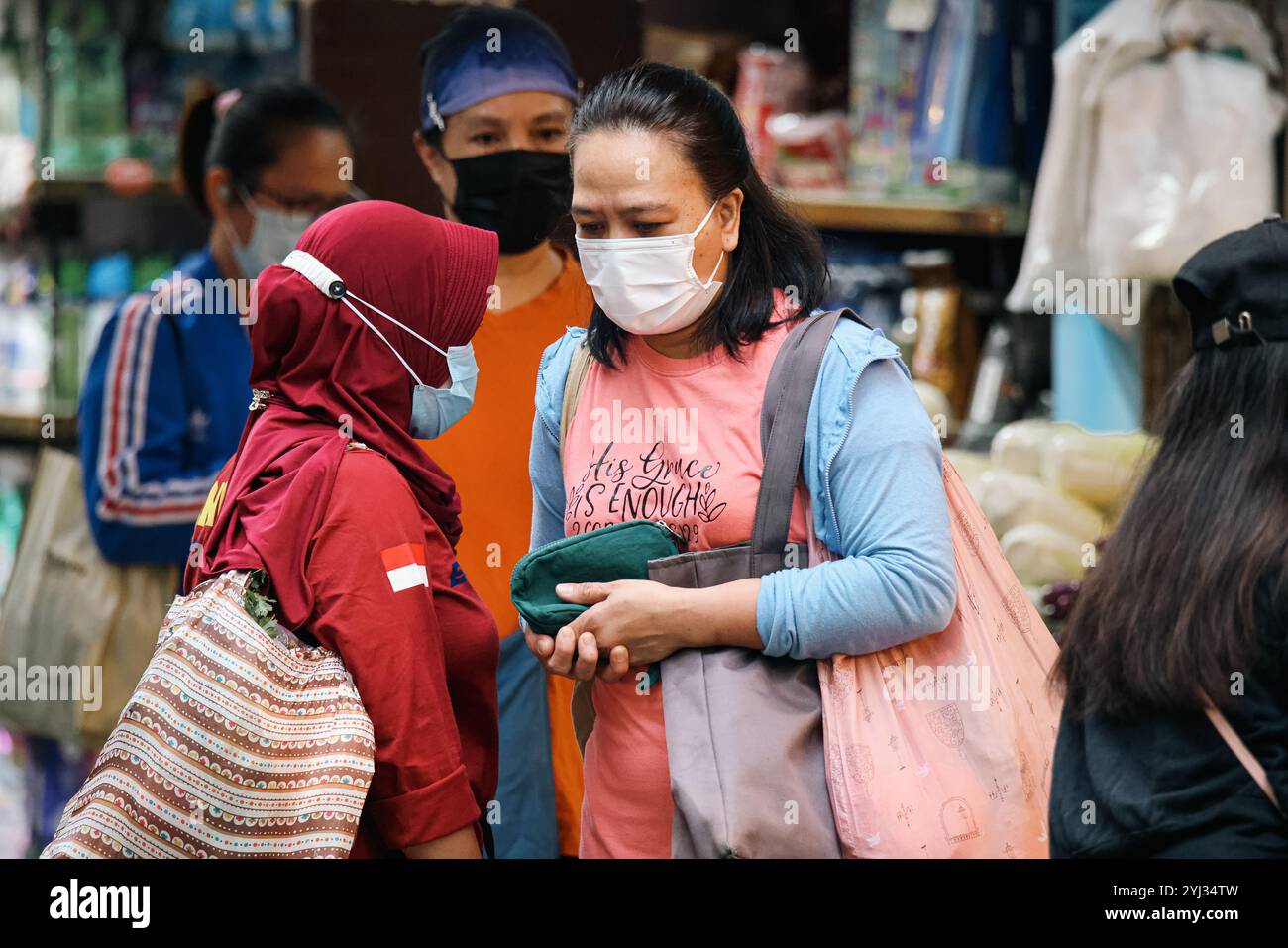 Due donne si impegnano in conversazione mentre fanno shopping in un vivace mercato di Hong Kong, mostrando l'atmosfera vivace della zona. Foto Stock