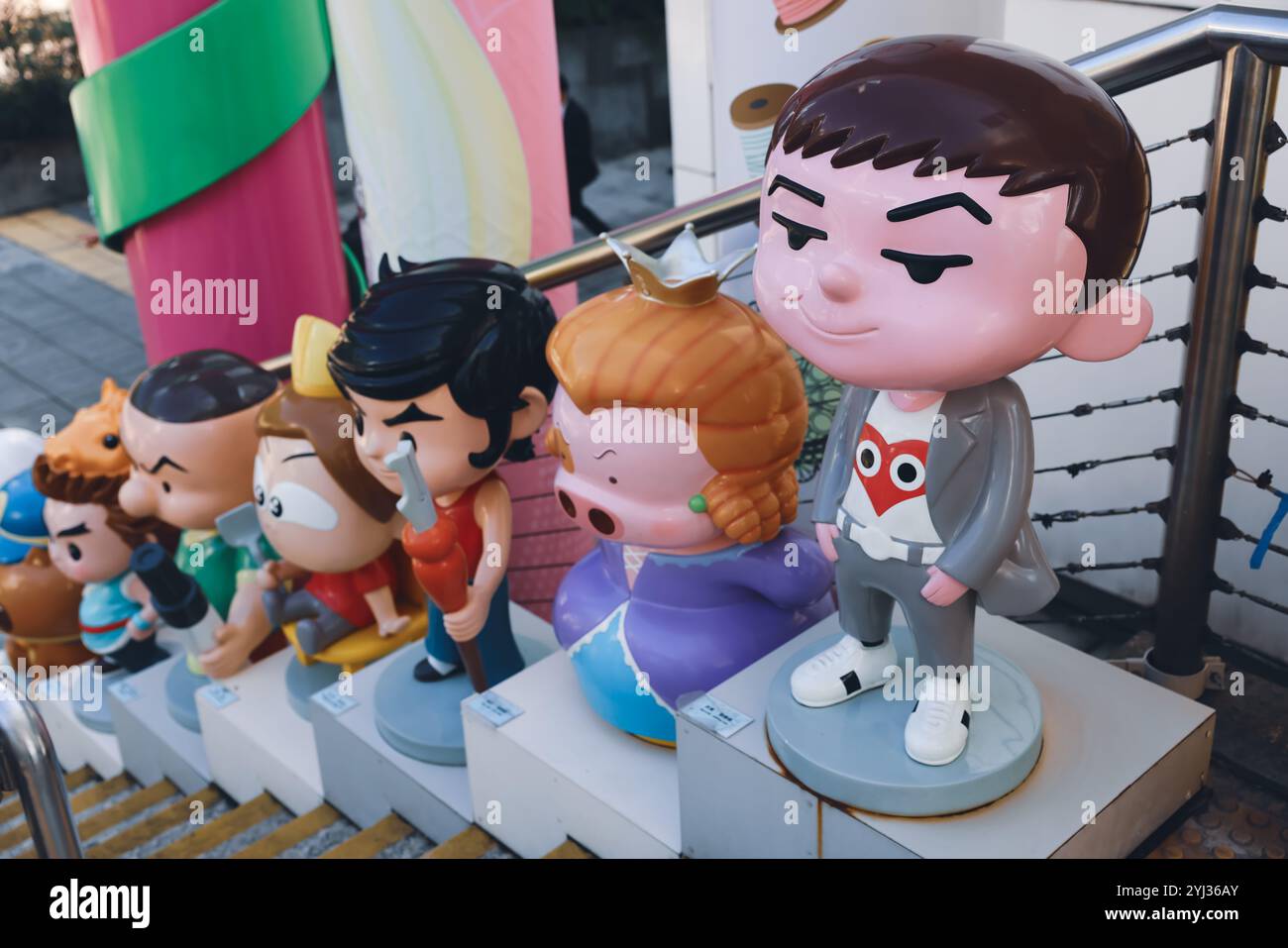 Una varietà di personaggi dei cartoni animati si erge sui gradini di Hong Kong, mostrando le loro caratteristiche distintive e i colori vivaci in un vivace ambiente urbano. Foto Stock