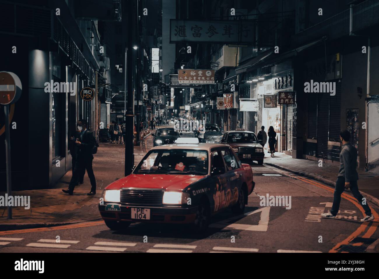 Un taxi rosso percorre una vivace strada di Hong Kong, illuminata da luci al neon e circondata da pedoni ed edifici. Foto Stock